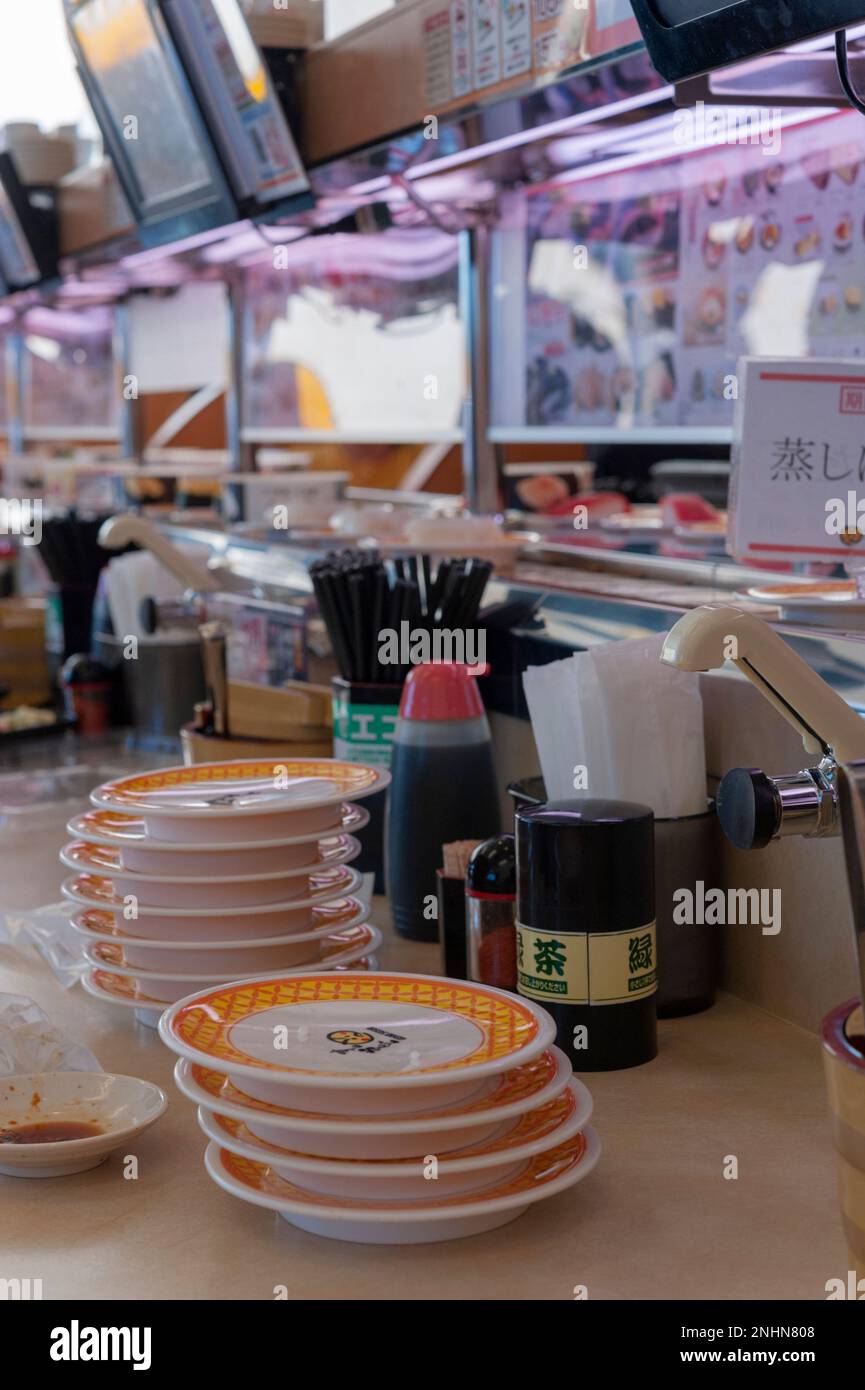 Montones de platos se acumulan rápidamente en un restaurante kaitenzushi, donde el sushi viaja en cintas transportadoras para llegar al cliente. Foto de stock