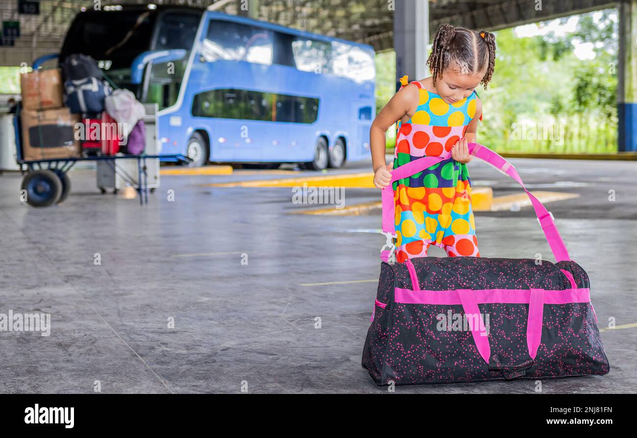 Pequeña chica latina y brasileña con una gran bolsa esperando un autobús en  la estación de autobuses Fotografía de stock - Alamy