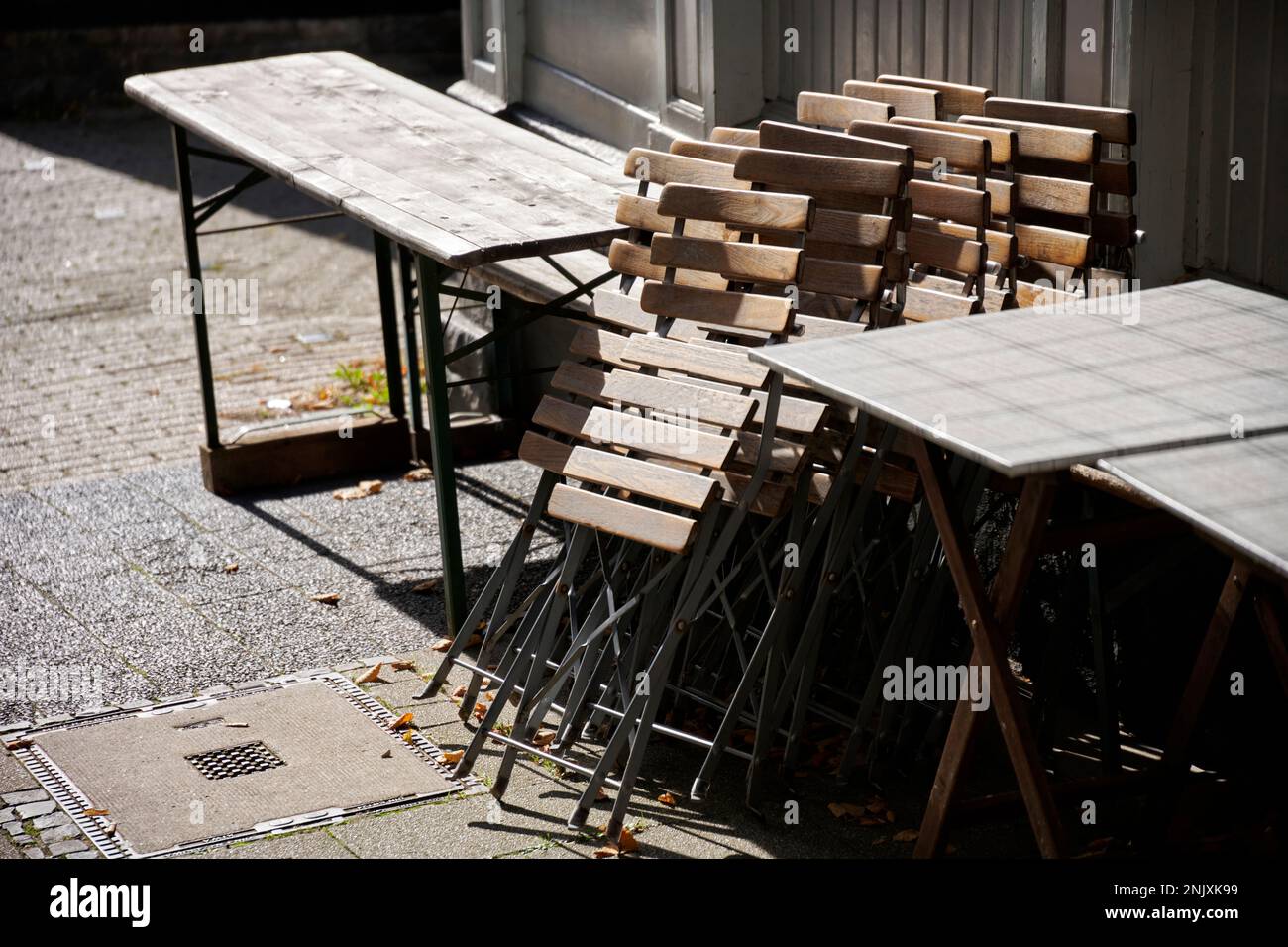 Zusammengeklappte Holzstühle im Aussengastrobereich in der Altstadt Hattingen. Sie werden von der Sonne beschienen. Foto de stock
