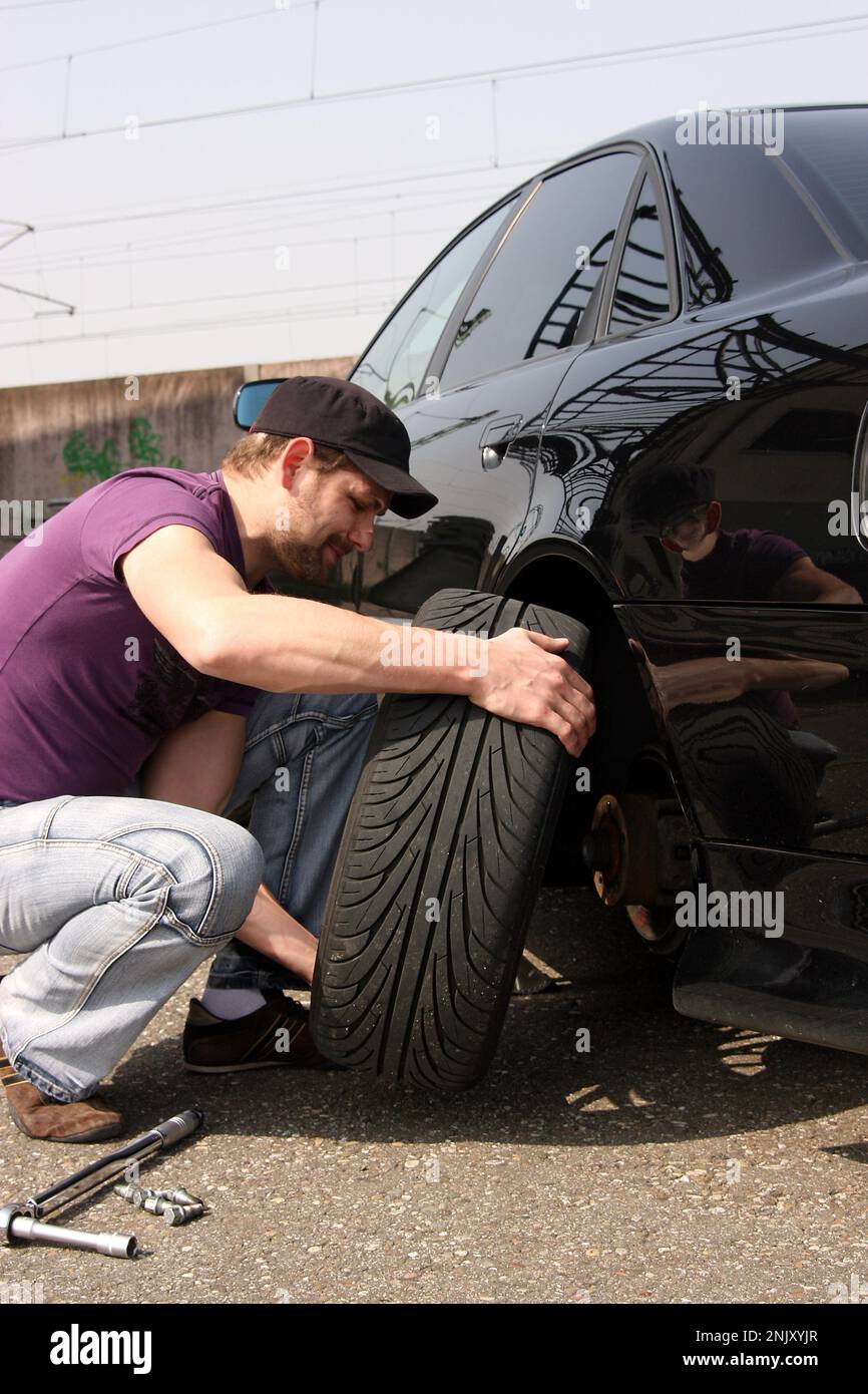 cambio de neumáticos, hombre joven cambia neumáticos de invierno a neumáticos sommer, imagen de la serie 7/9 Foto de stock