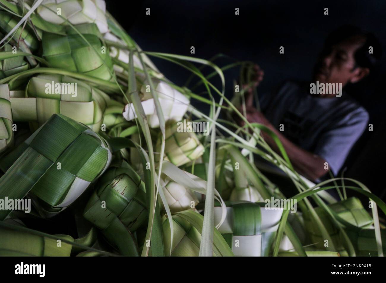 Indonesian vendors weave palm leaves used to make traditional rice ...