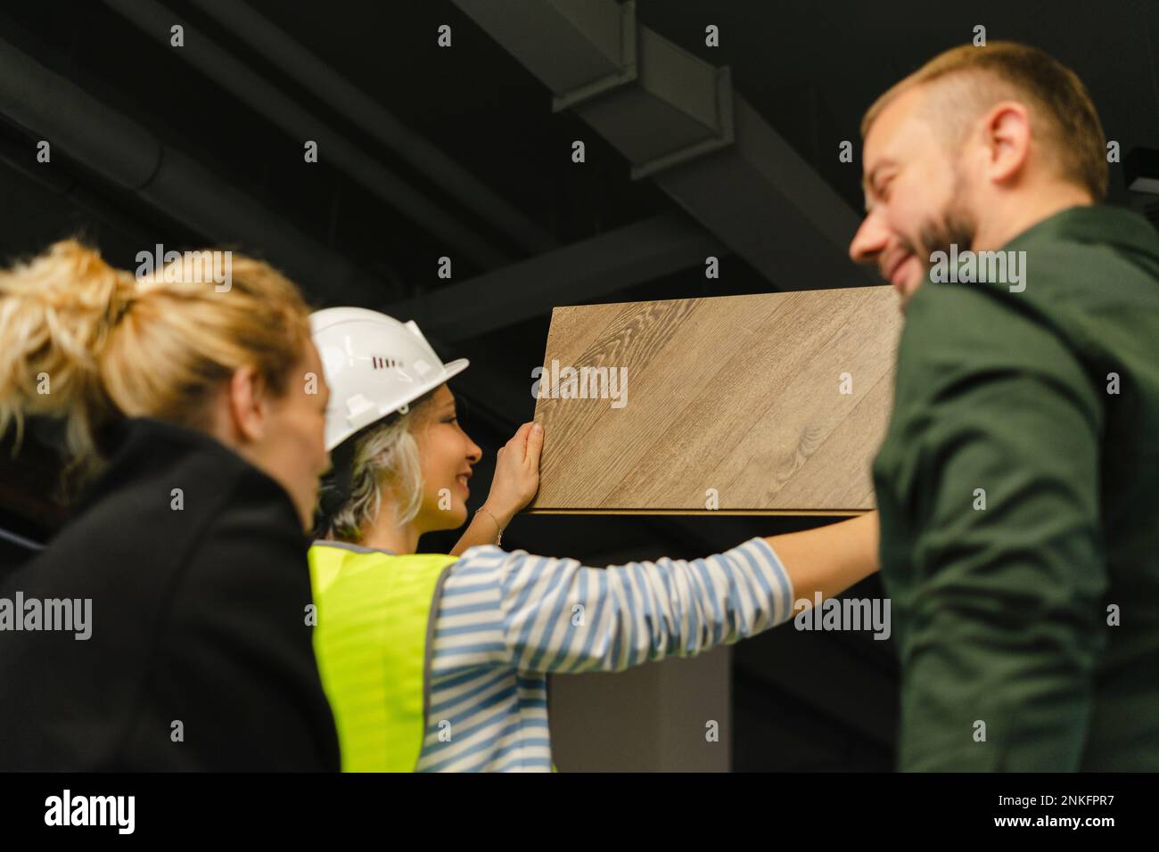 Hombre de negocios, mujer e ingeniero examinando el tablero de madera en la oficina Foto de stock
