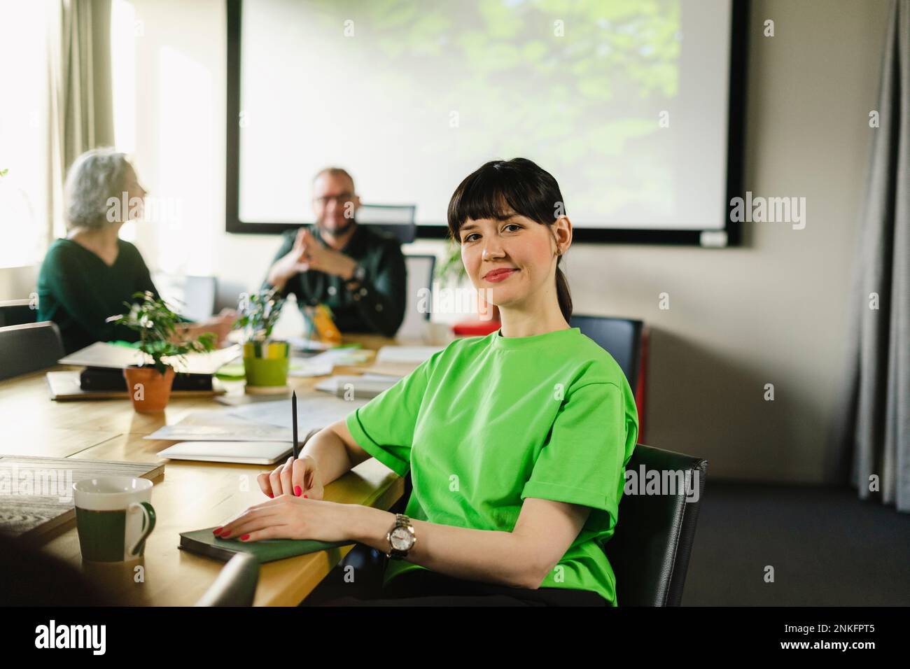 Retrato de mujer con camiseta verde durante una reunión en la sala de conferencias Foto de stock