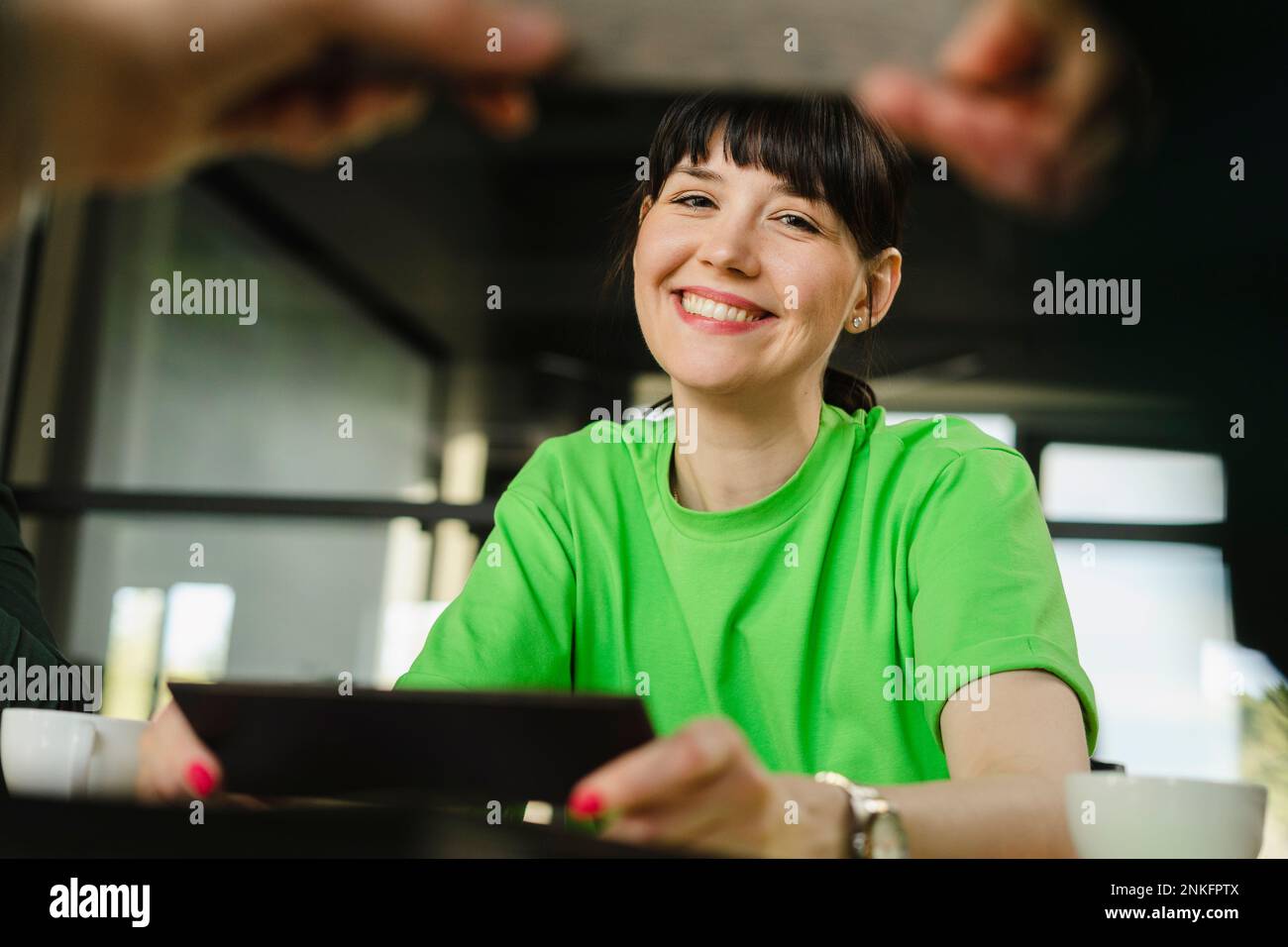 Mujer sonriente con camiseta verde en la oficina Foto de stock