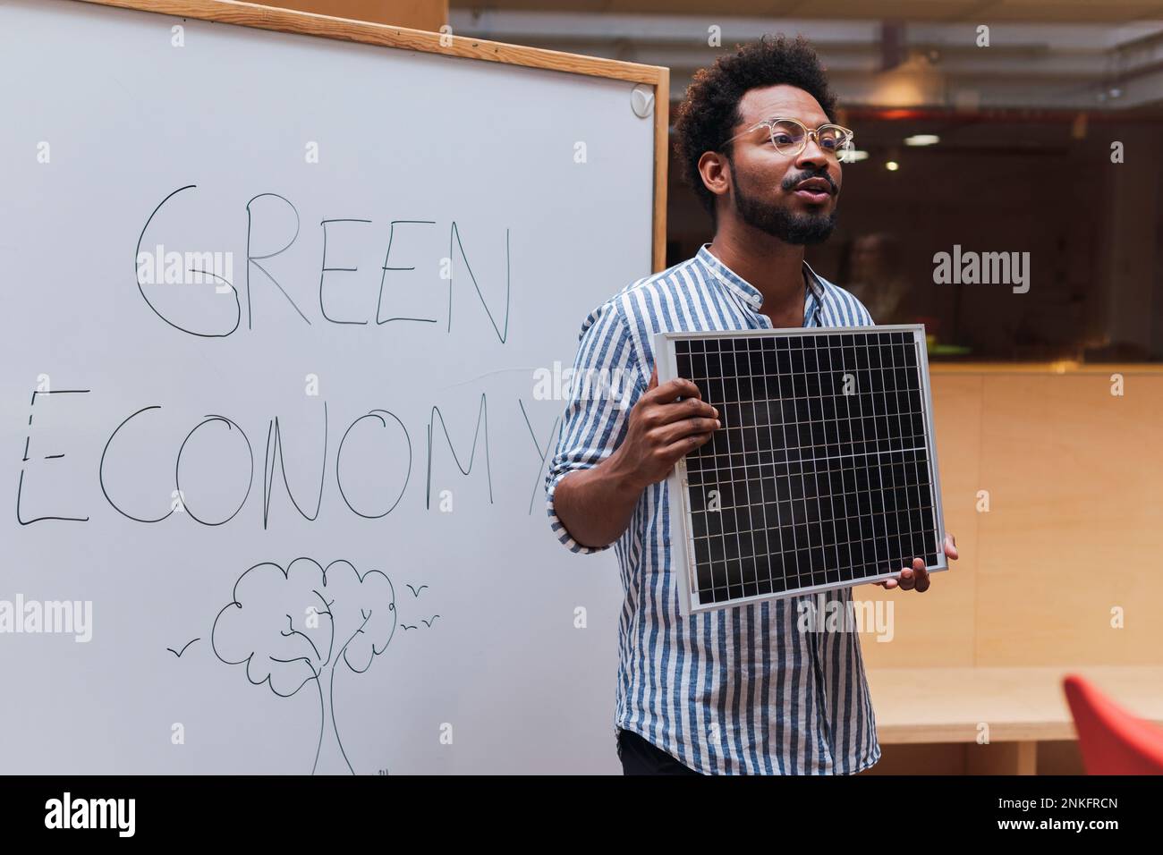 Hombre de negocios dando una presentación en la oficina que sostiene el panel solar Foto de stock