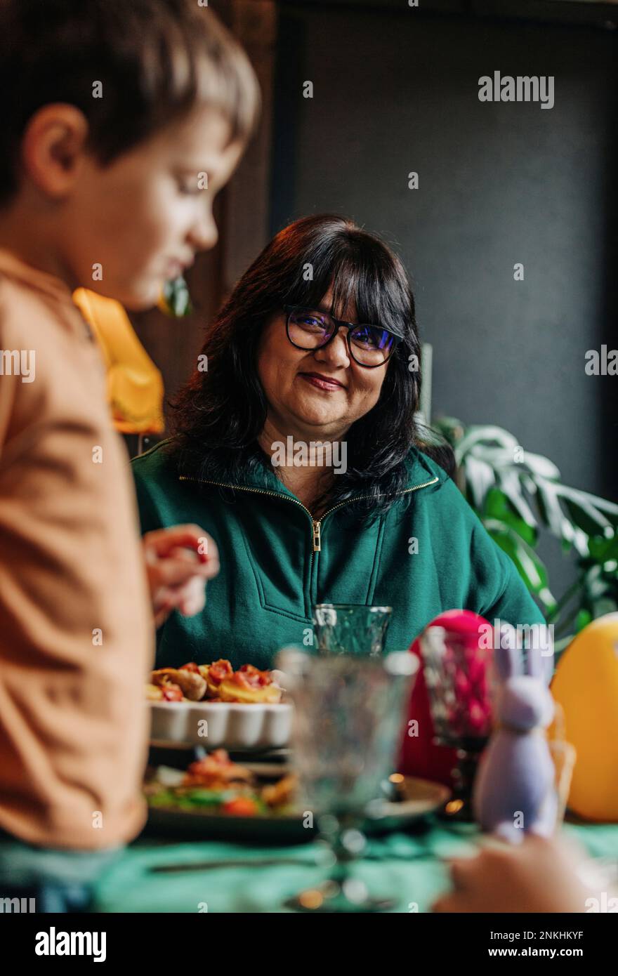 Abuela sonriente con el nieto que tiene la cena de Pascua en casa Foto de stock