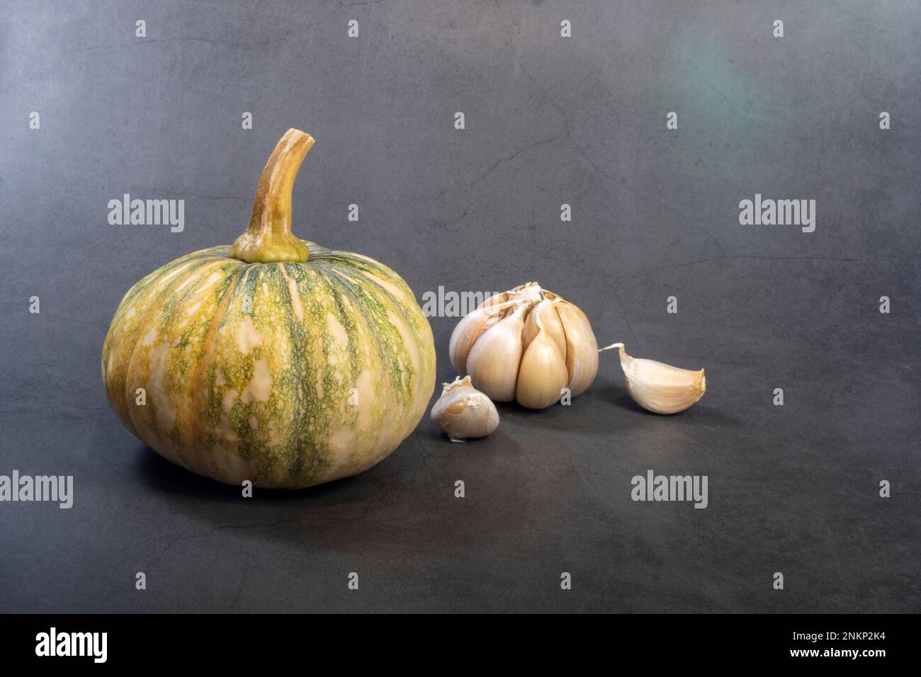 Calabaza cruda y verdura de ajo sobre un fondo oscuro. Foto de stock