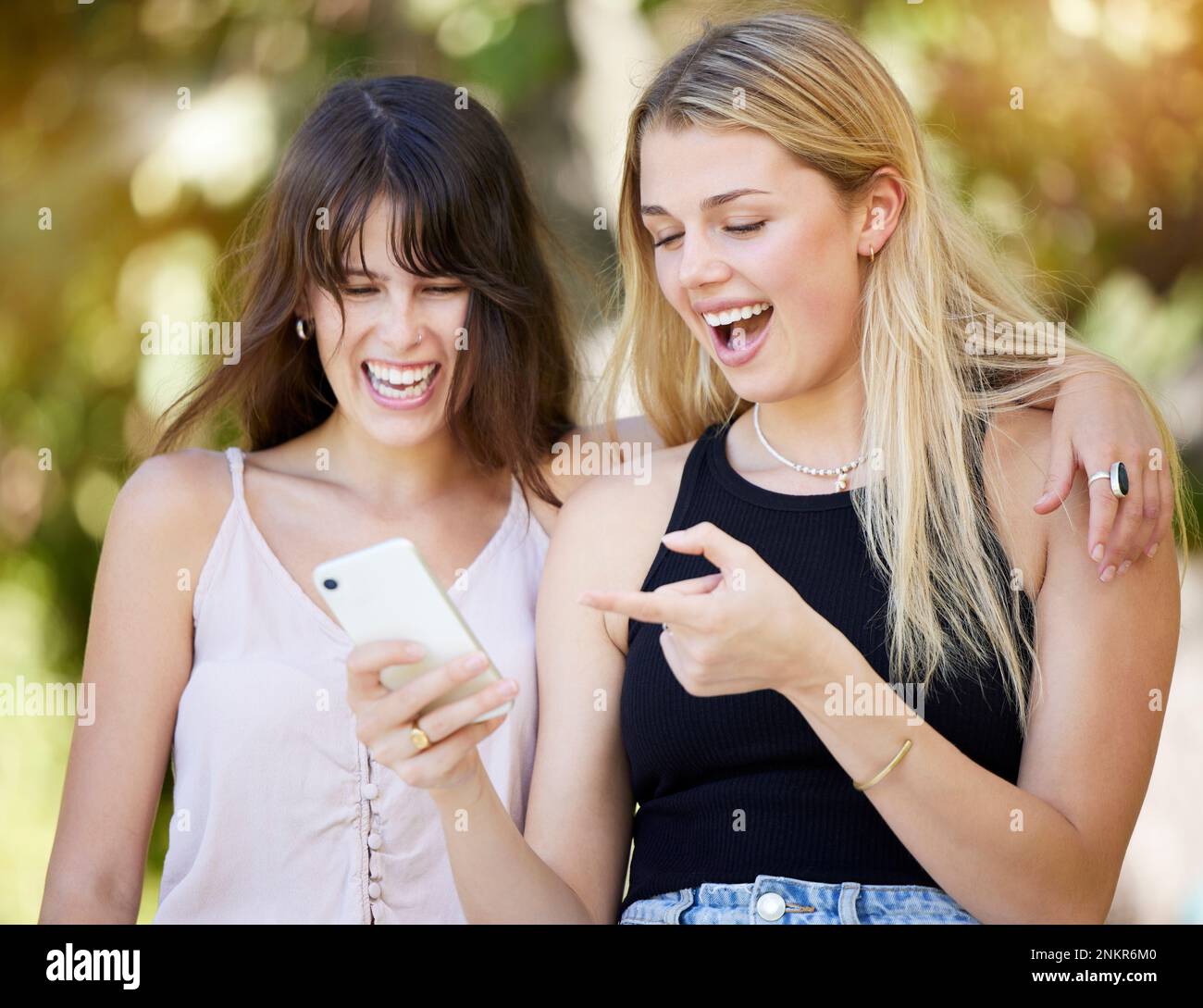 Reír, sonreír o amigas con el teléfono en el parque para meme en línea, leer un blog de cómics o redes sociales. Pareja, feliz o mujeres en 5g Smartphone para Foto de stock