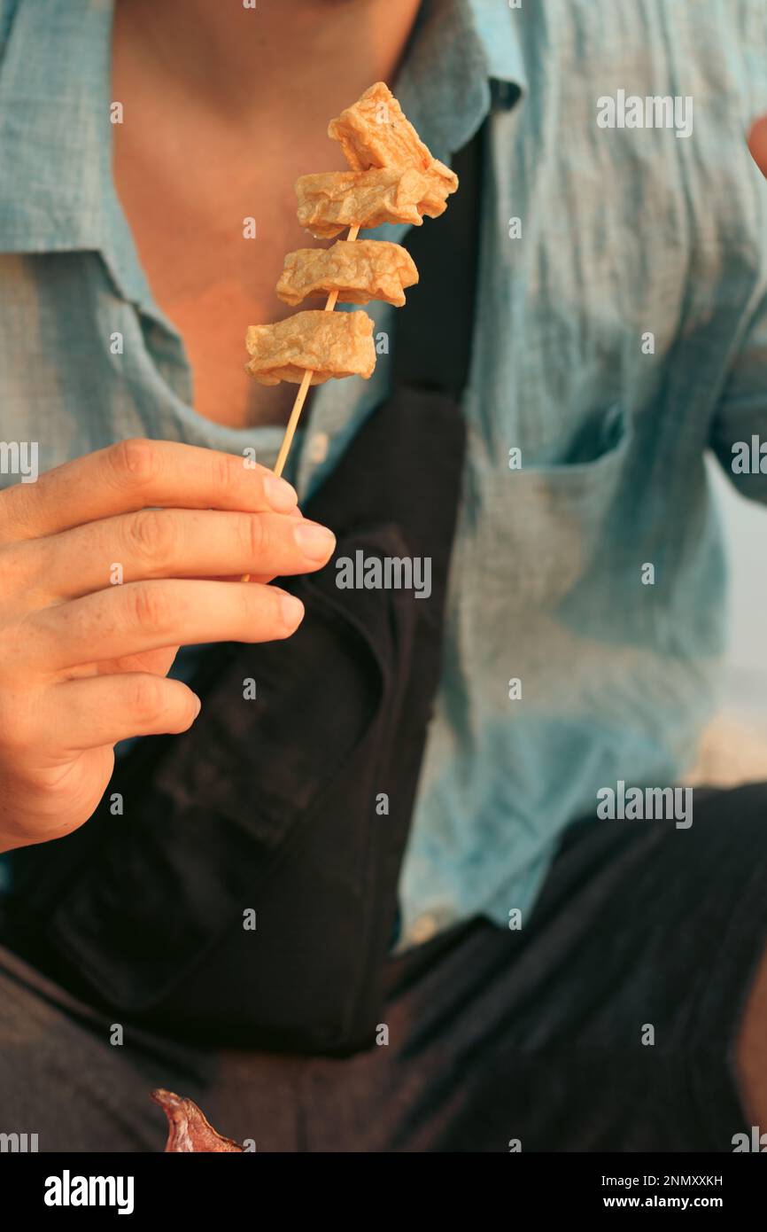 Turista comiendo Eomuk Bokkeum o brochetas de pastel de pescado coreano  como comida callejera Fotografía de stock - Alamy