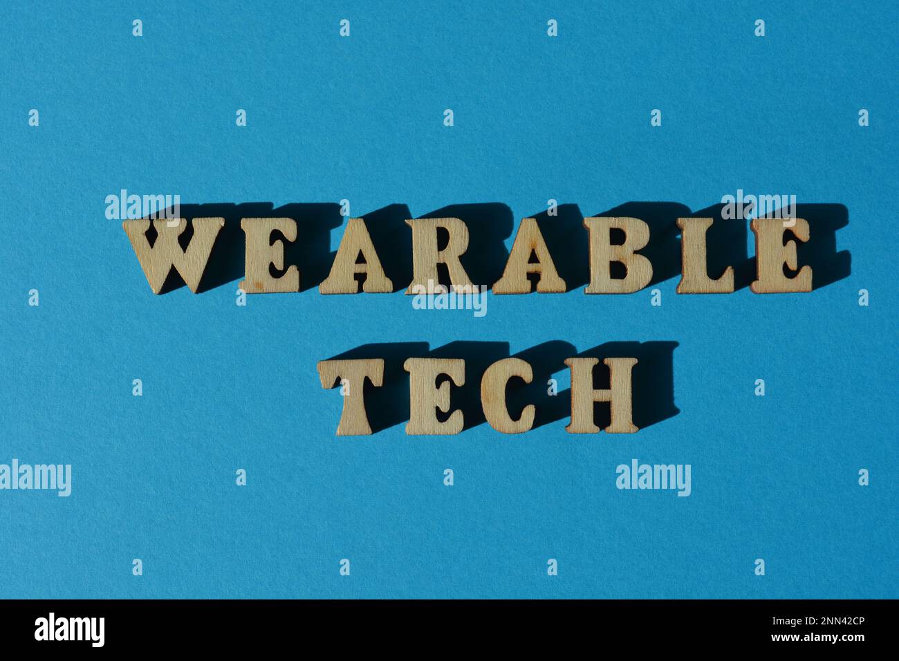 Wearable Tech, palabras en letras de alfabeto de madera aisladas sobre fondo azul Foto de stock