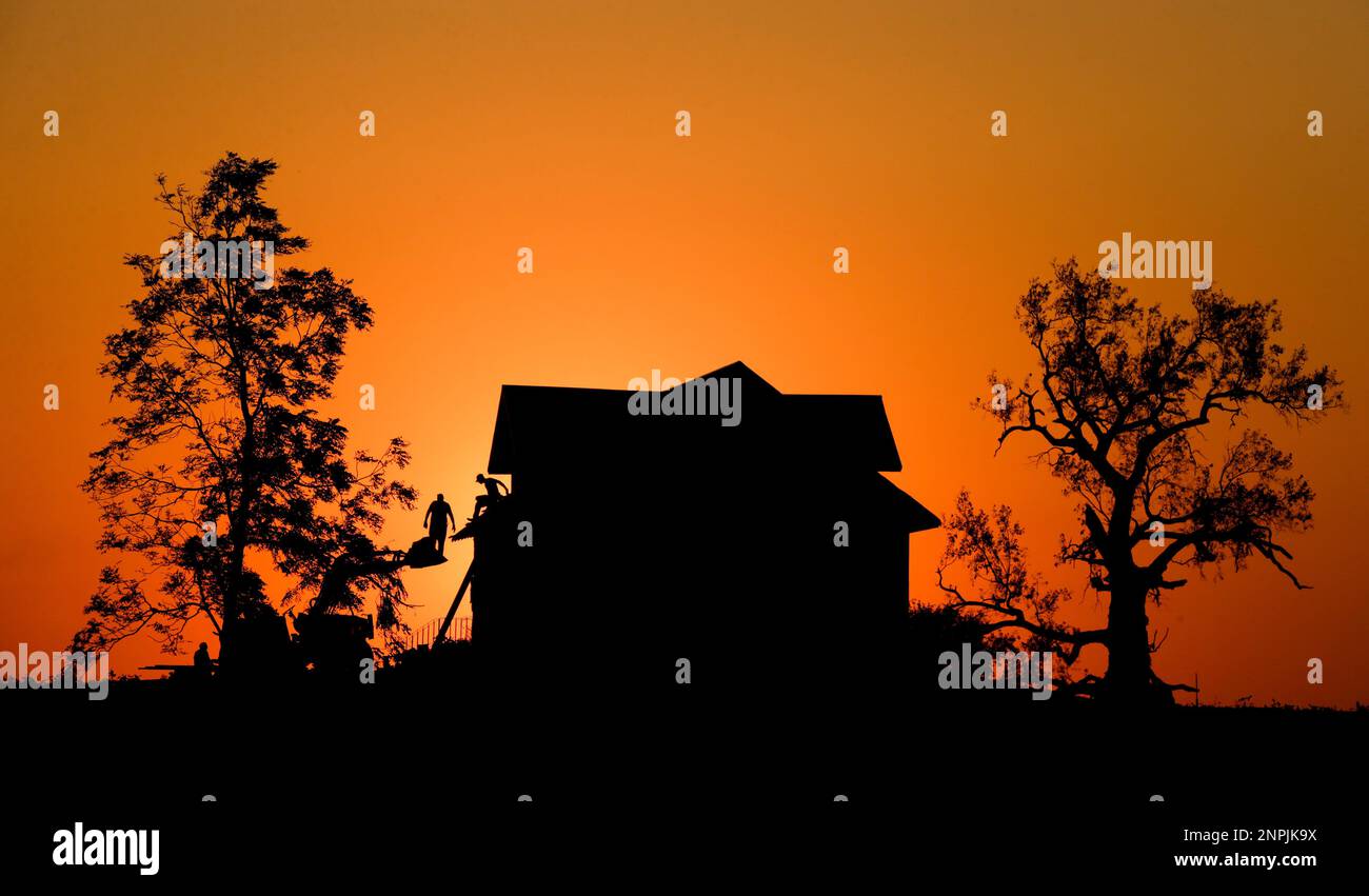 Damaged trees flank a house as members of the Lang family come off the