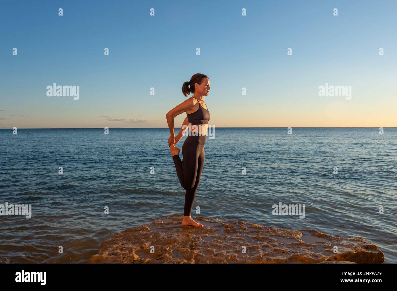 FIT, mujer deportiva estirándose junto al mar. Foto de stock