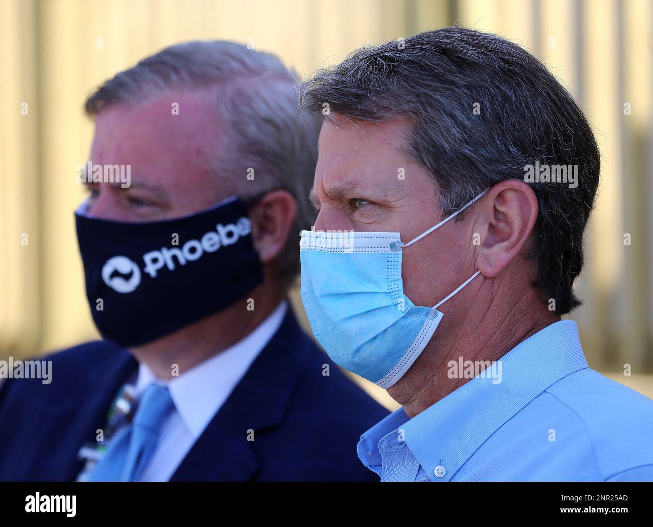 Gov. Brian Kemp, right, wears a mask while touring a temporary
