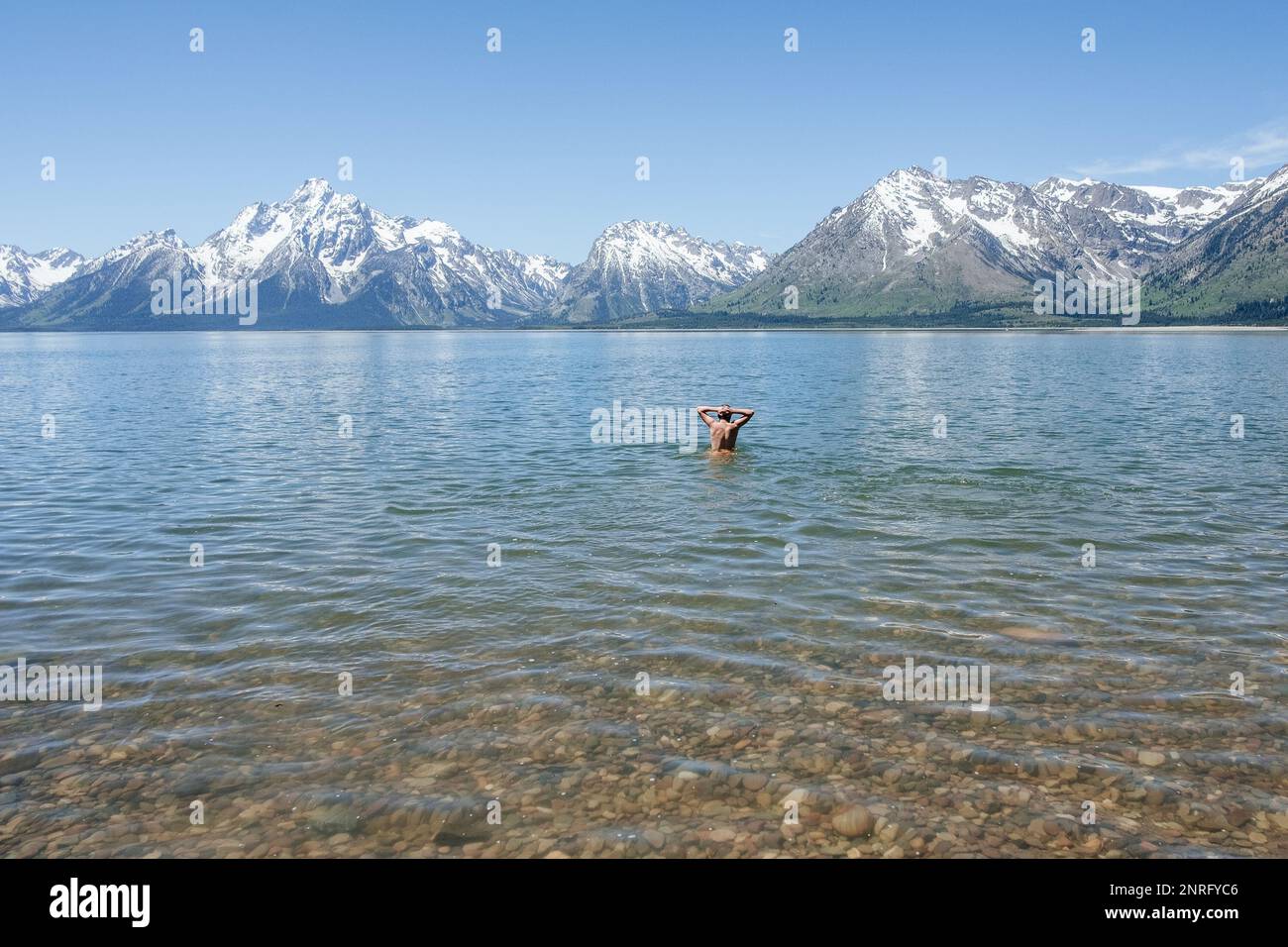 Hombre de pie en aguas profundas en lago alpino Foto de stock