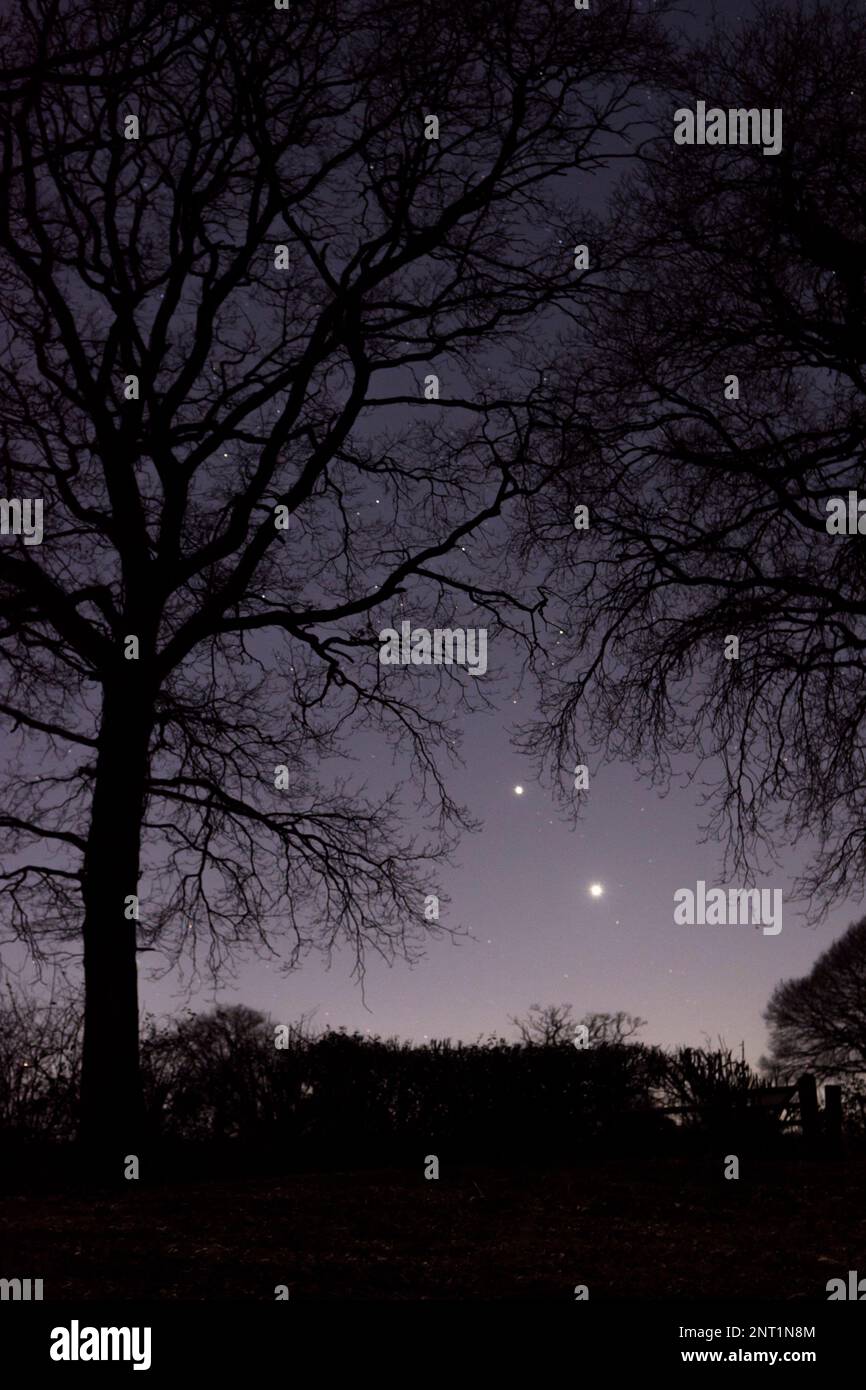 Dos planetas cerca de la conjunción, Júpiter sobre Venus, finales de febrero de 2023, brillando intensamente bajo en el cielo nocturno sobre el Reino Unido Foto de stock
