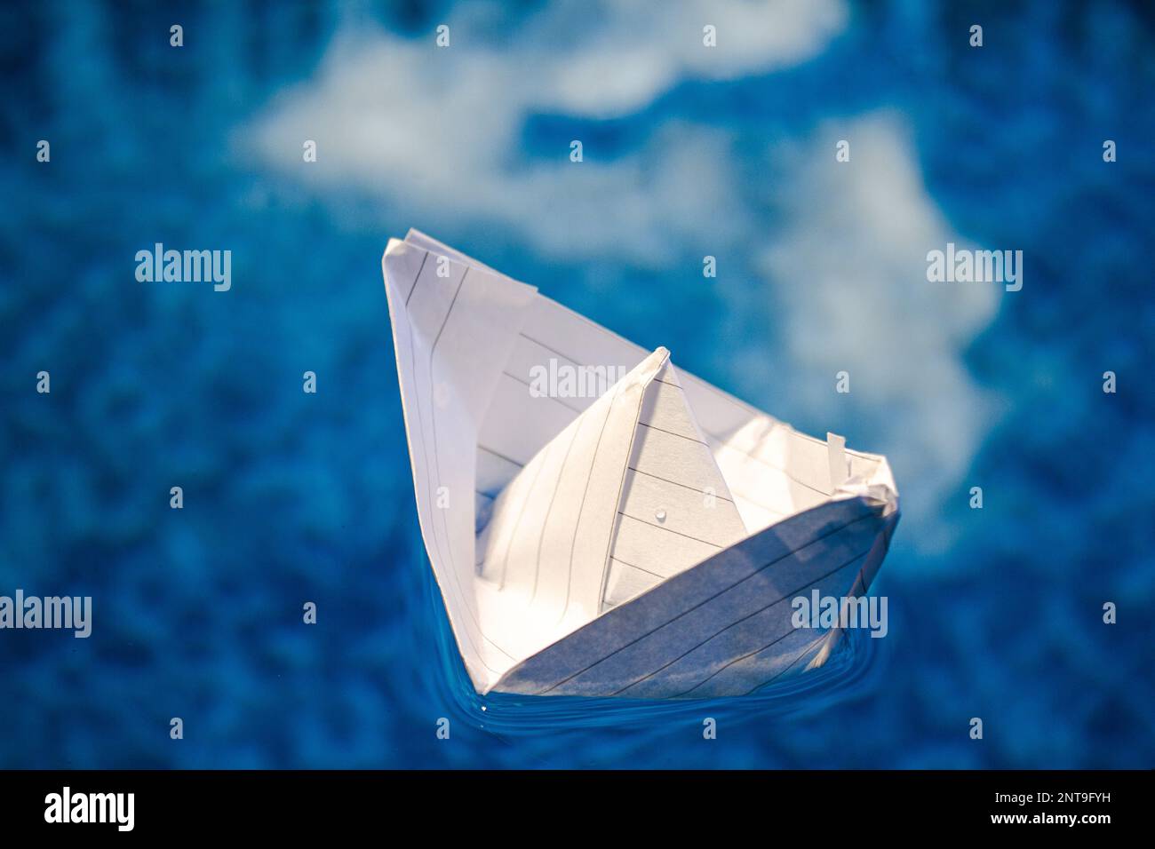 Barco de papel plegado flotando en el agua Foto de stock