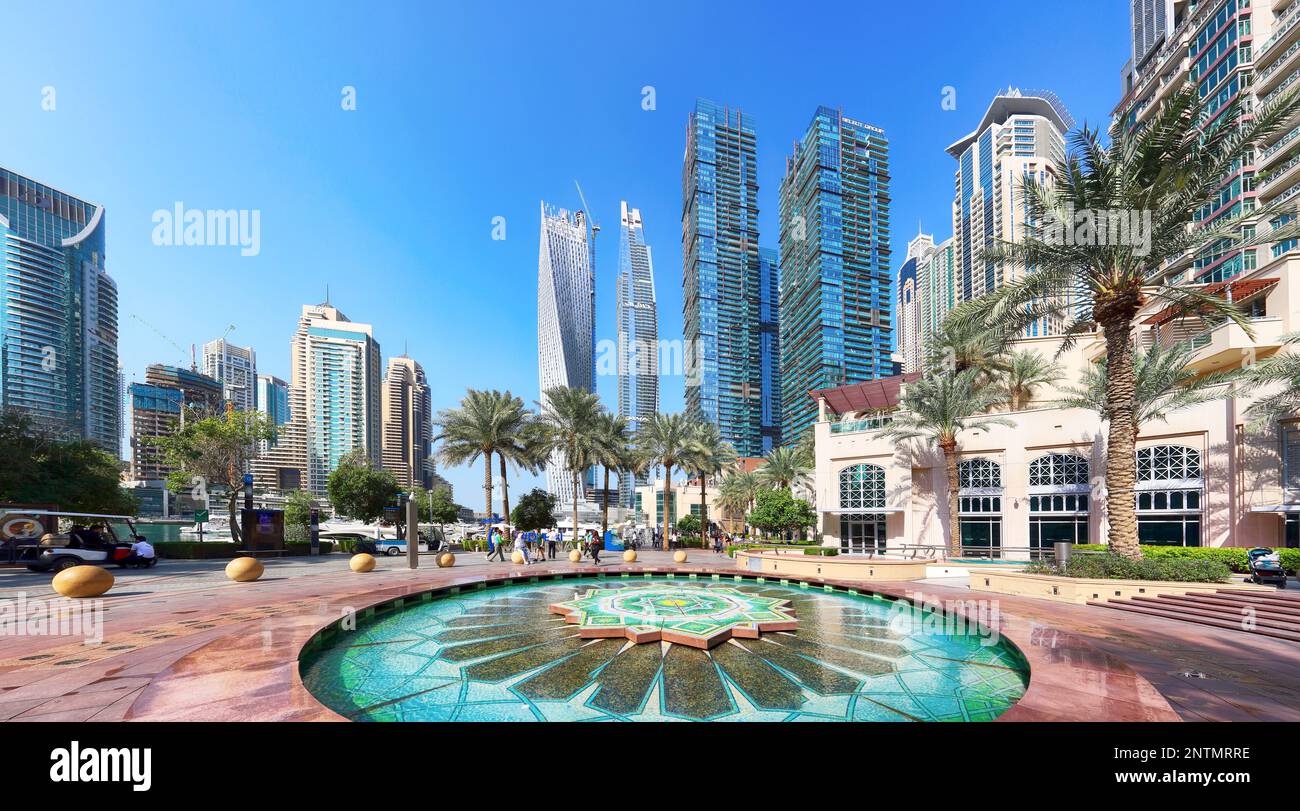 Dubai, Emiratos Árabes Unidos, 11 2023 de enero: Fuente en Dubai Marina canal y paseo marítimo en hermoso día de verano, Dubai, Emiratos Árabes Unidos Foto de stock