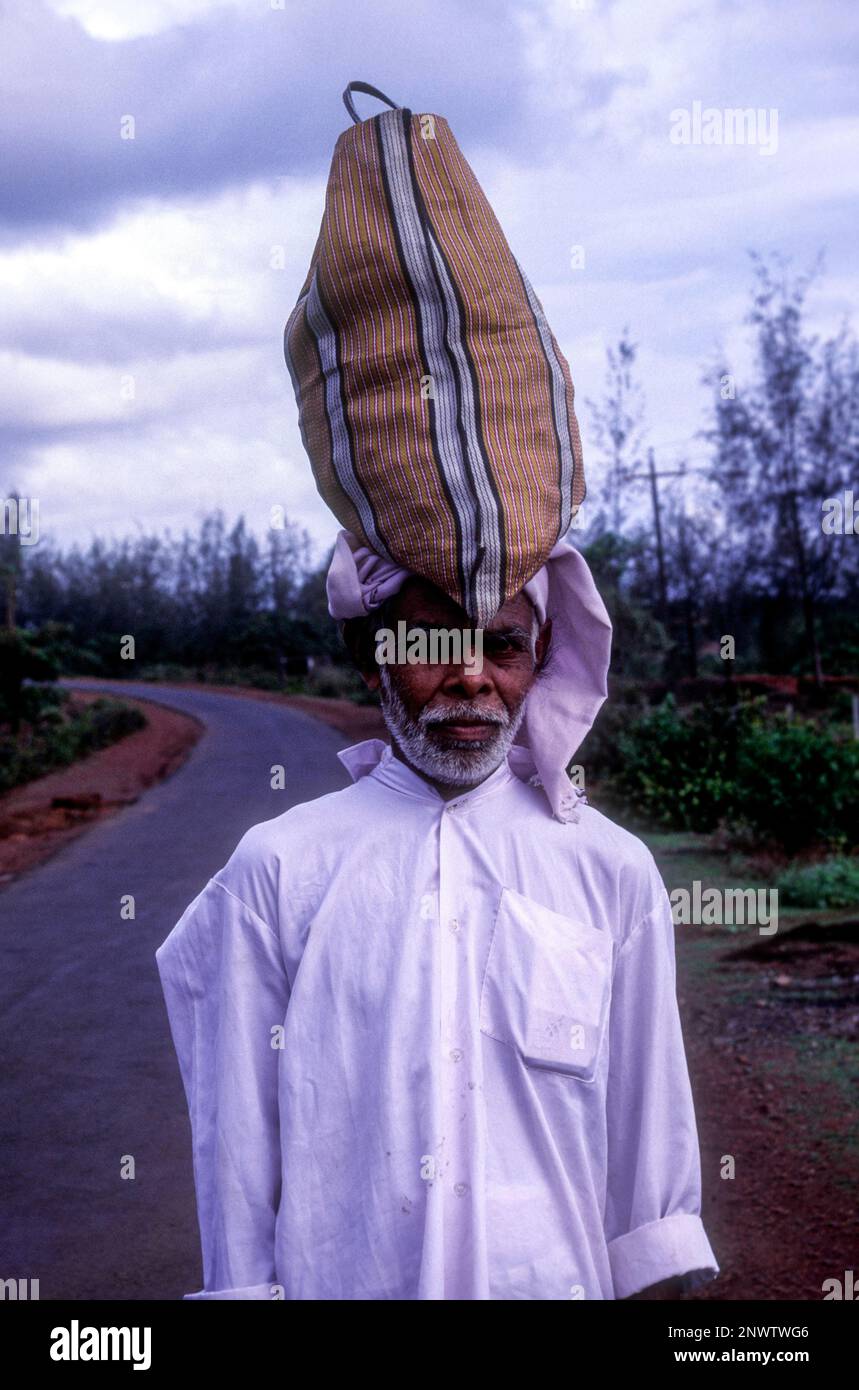 Un hombre que lleva una bolsa sobre su cabeza en la carretera, Kerala, el sur de la India, la India, Asia Foto de stock