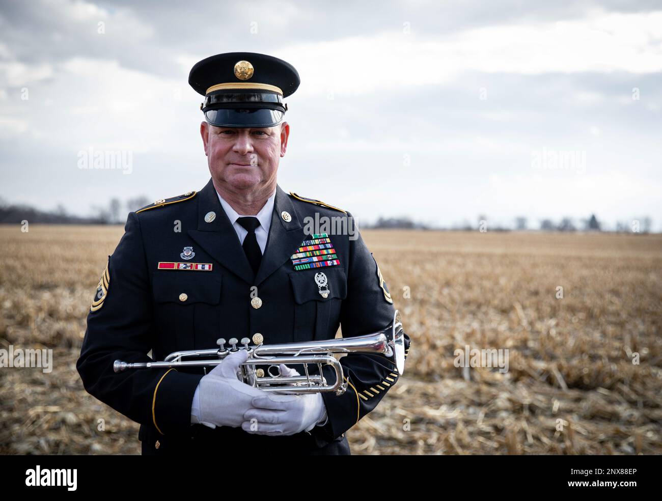El sargento 1st Clase Jeffrey Six, nativo de Fairfield, Iowa, y ex miembro de la Banda 34th del Ejército, Guardia Nacional del Ejército de Iowa, posa con su trompeta en el Cementerio de Saint Mary en Wilton, Iowa, el 16 de enero de 2023. Six se jubiló después de casi 40 años de servicio el 28 de diciembre de 2022. Esta fue su primera vez tocando con el equipo de honores funerarios de la Guardia Nacional de Iowa como jubilado. Six comenzó a tocar trompeta en la banda de marcha de la escuela secundaria cuando su director de banda y ex comandante de la Banda del Ejército 34th lo alentó a alistarse. Desde entonces, Six ha actuado en todos los rincones del estado de Iowa y en el extranjero, Foto de stock