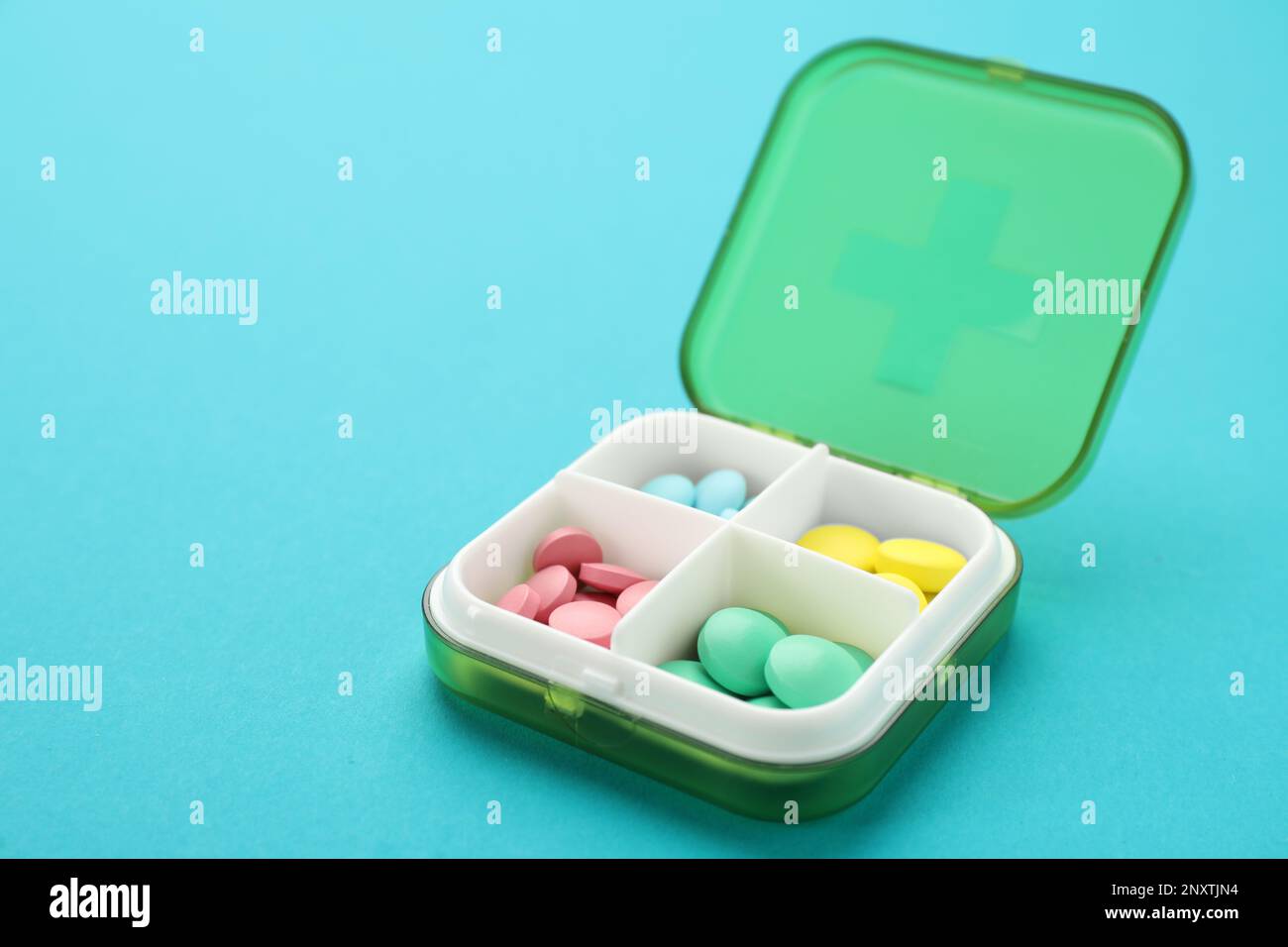 https://c8.alamy.com/compes/2nxtjn4/caja-de-plastico-con-diferentes-pildoras-sobre-fondo-azul-claro-2nxtjn4.jpg