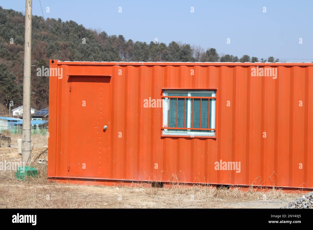 Contenedor de envío naranja brillante en el sitio de construcción Foto de stock