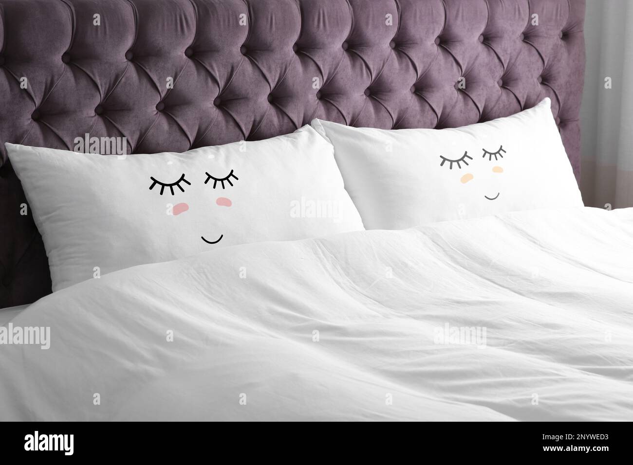 Almohadas suaves con caras lindas en una cama c moda por encima