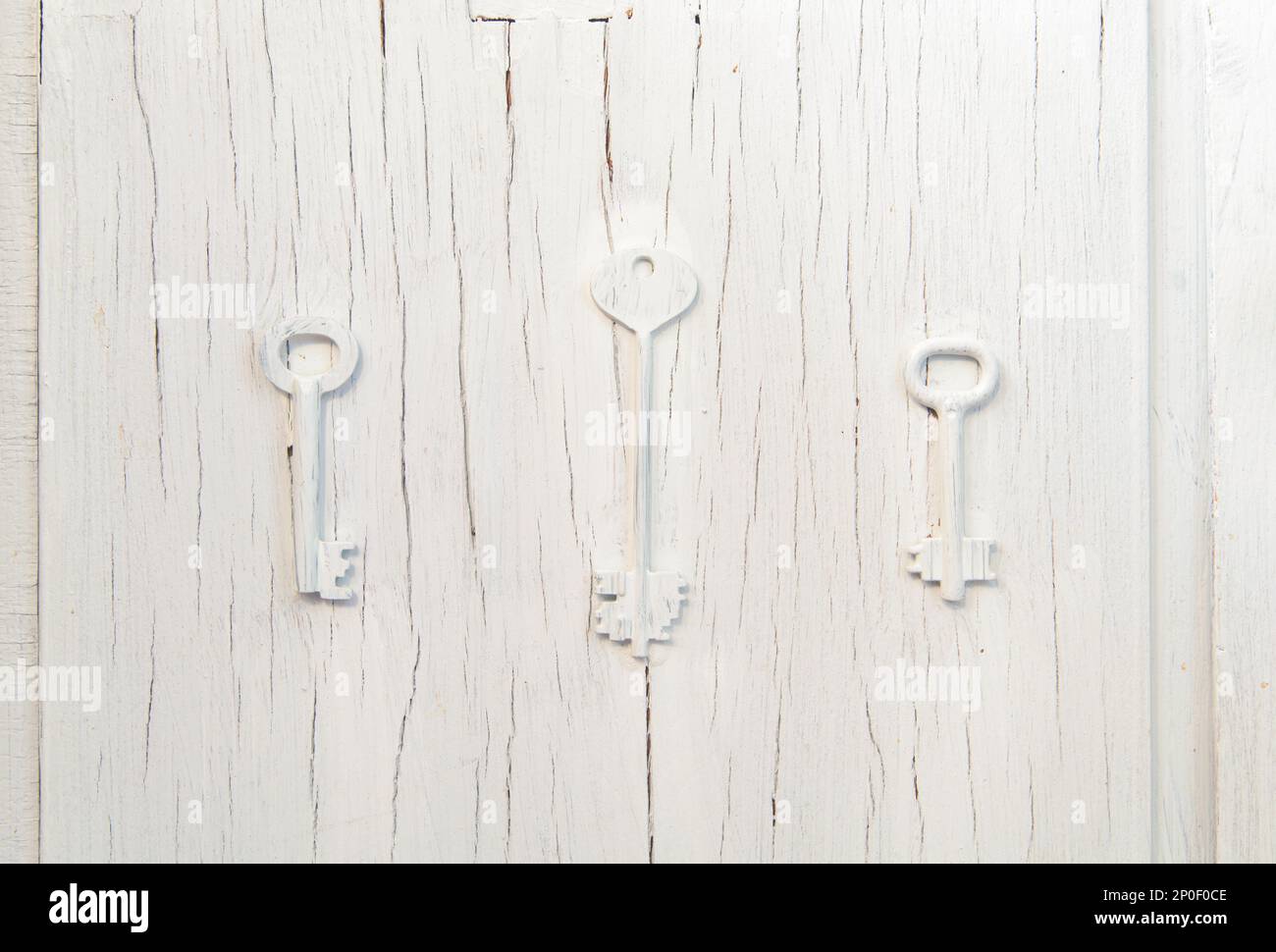 Tres teclas de decoración de moda en una vieja puerta agrietada gris, diseño abstracto vintage cluse-up de fondo. Elección del problema de ruta Foto de stock
