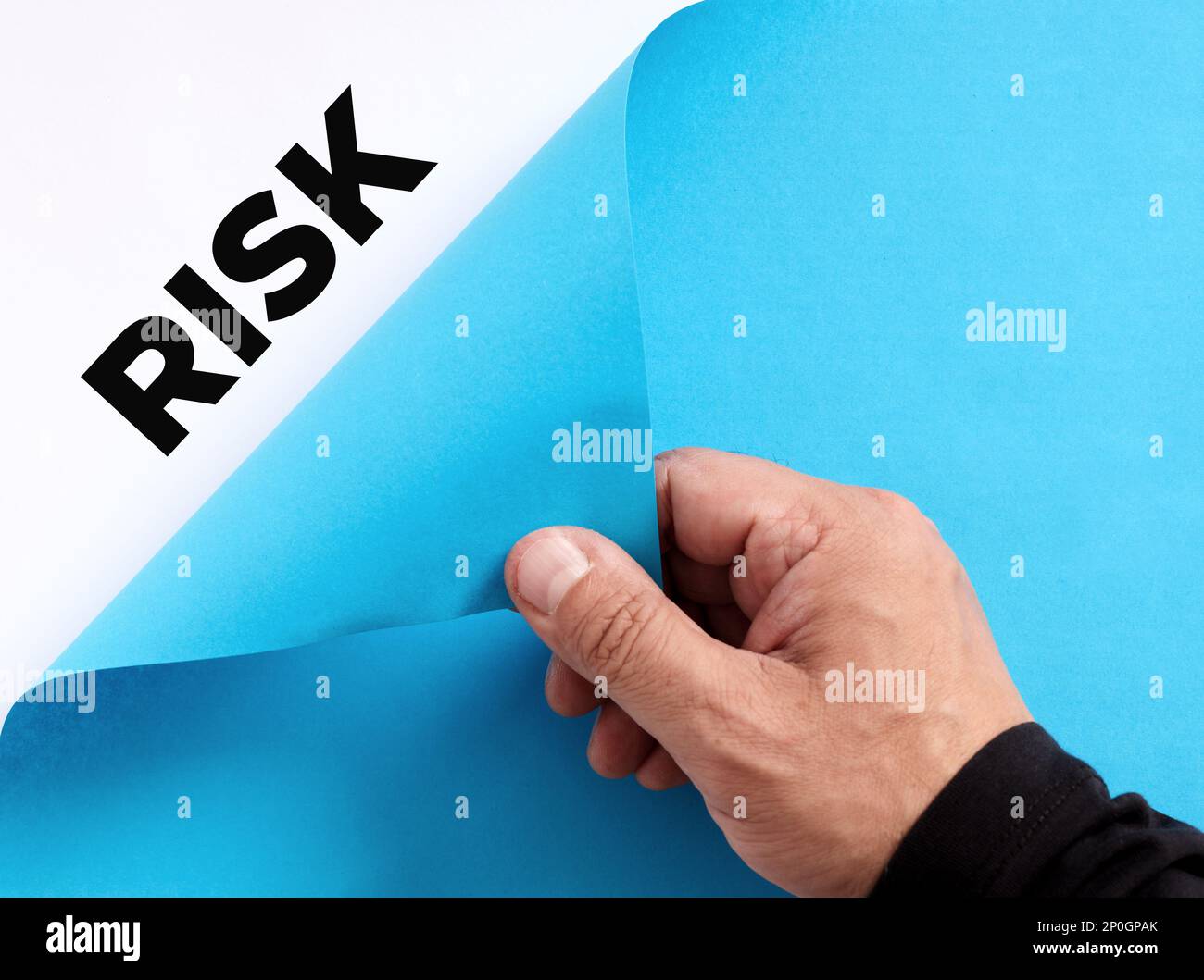 Para descubrir el concepto oculto de riesgos empresariales. Mano masculina abre el papel azul y revela la palabra riesgo. Foto de stock