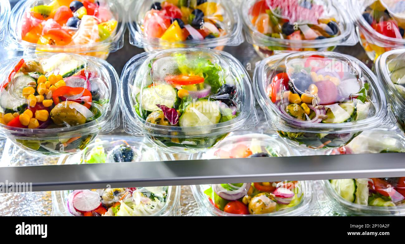 Cajas de plástico con ensaladas de frutas y verduras preenvasadas, puestas a la venta en un refrigerador comercial Foto de stock