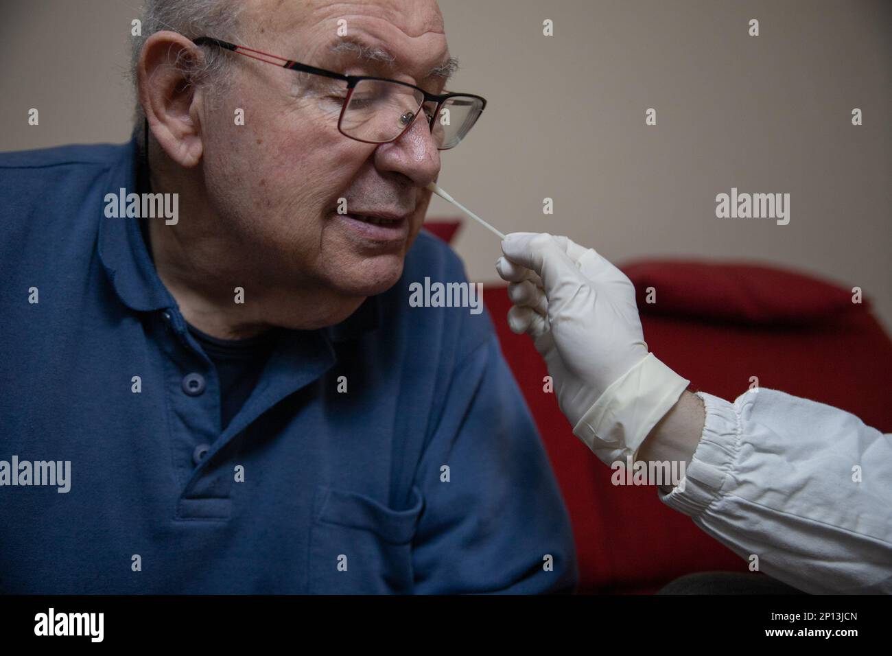 Un anciano realiza una prueba de COVID con un hisopo molecular insertado en su fosa nasal. Foto de stock