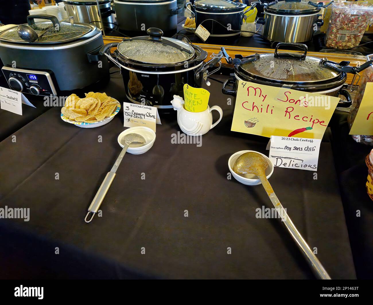 Fila de crockpots con patatas fritas y cubiertos para un concurso de cocina de chile Foto de stock