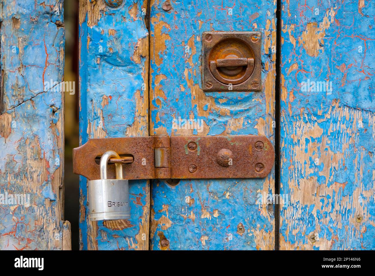 Cerradura y candado en una puerta de personal de madera pintada de azul afligido Foto de stock