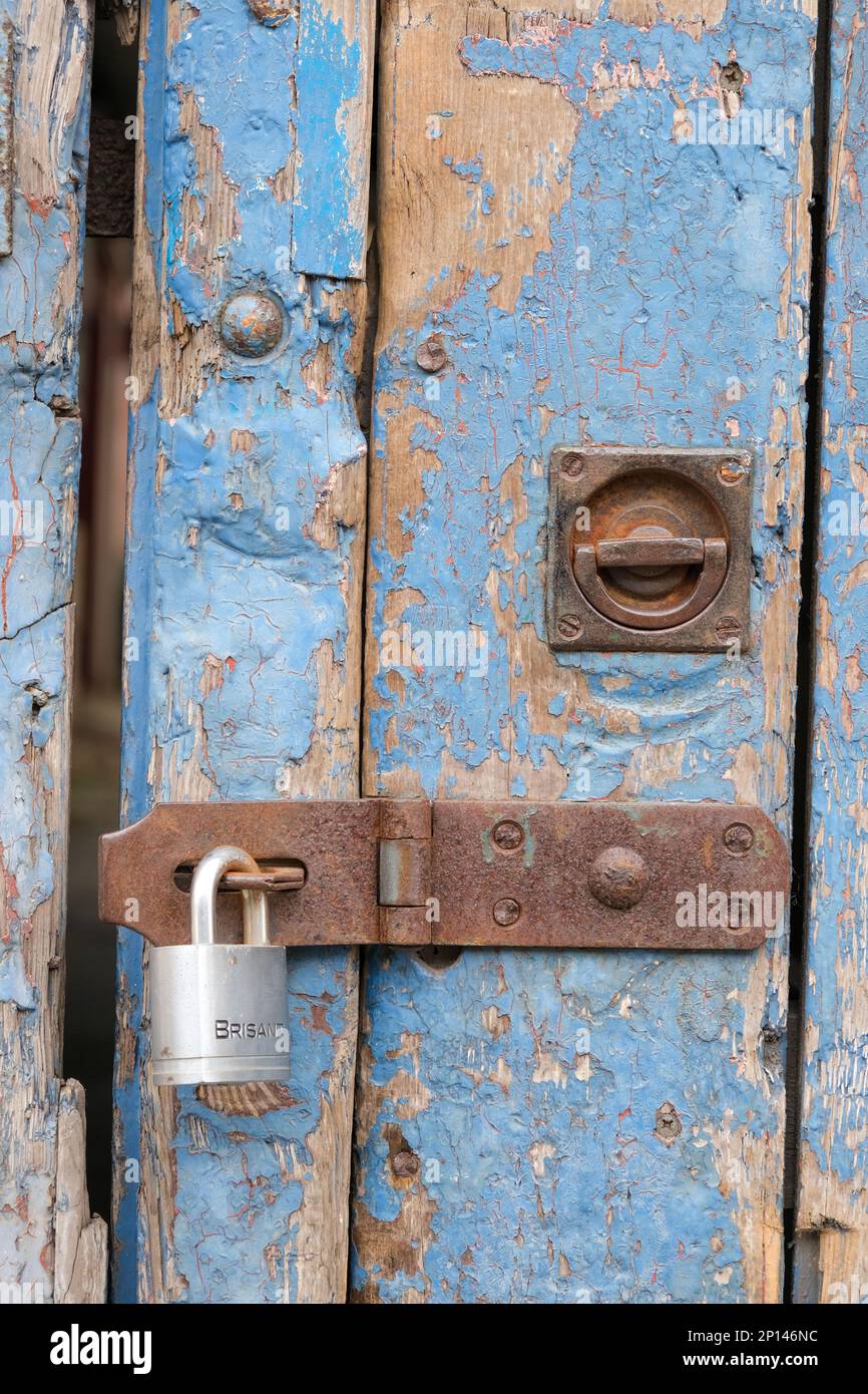 Cerradura y candado en una puerta de personal de madera pintada de azul afligido Foto de stock