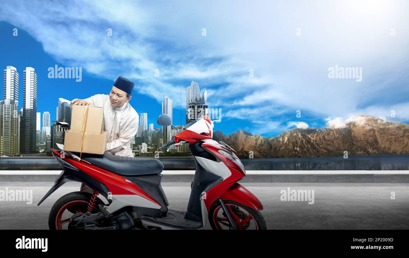 Hombre musulmán asiático que ata la caja en la motocicleta se prepara para el mudik en la calle Foto de stock