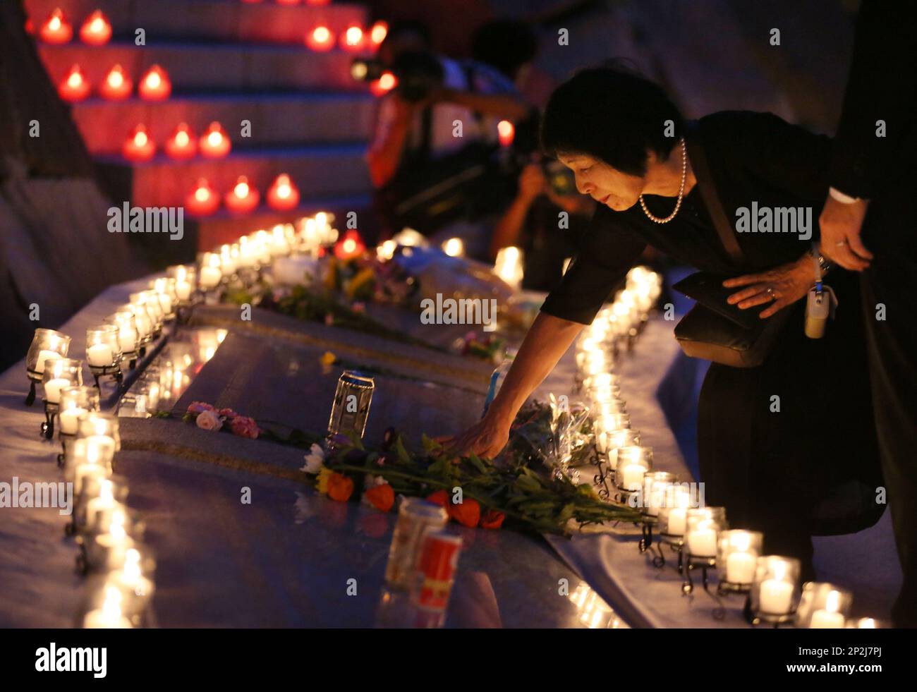 Bereaved family members pray in front of candles paying tribute to