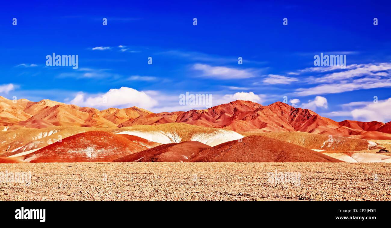 Hermoso paisaje desértico espectacular con colinas de arenisca roja y naranja y montañas en contraste con el cielo azul del verano - Salar de Atacama, Chile Foto de stock