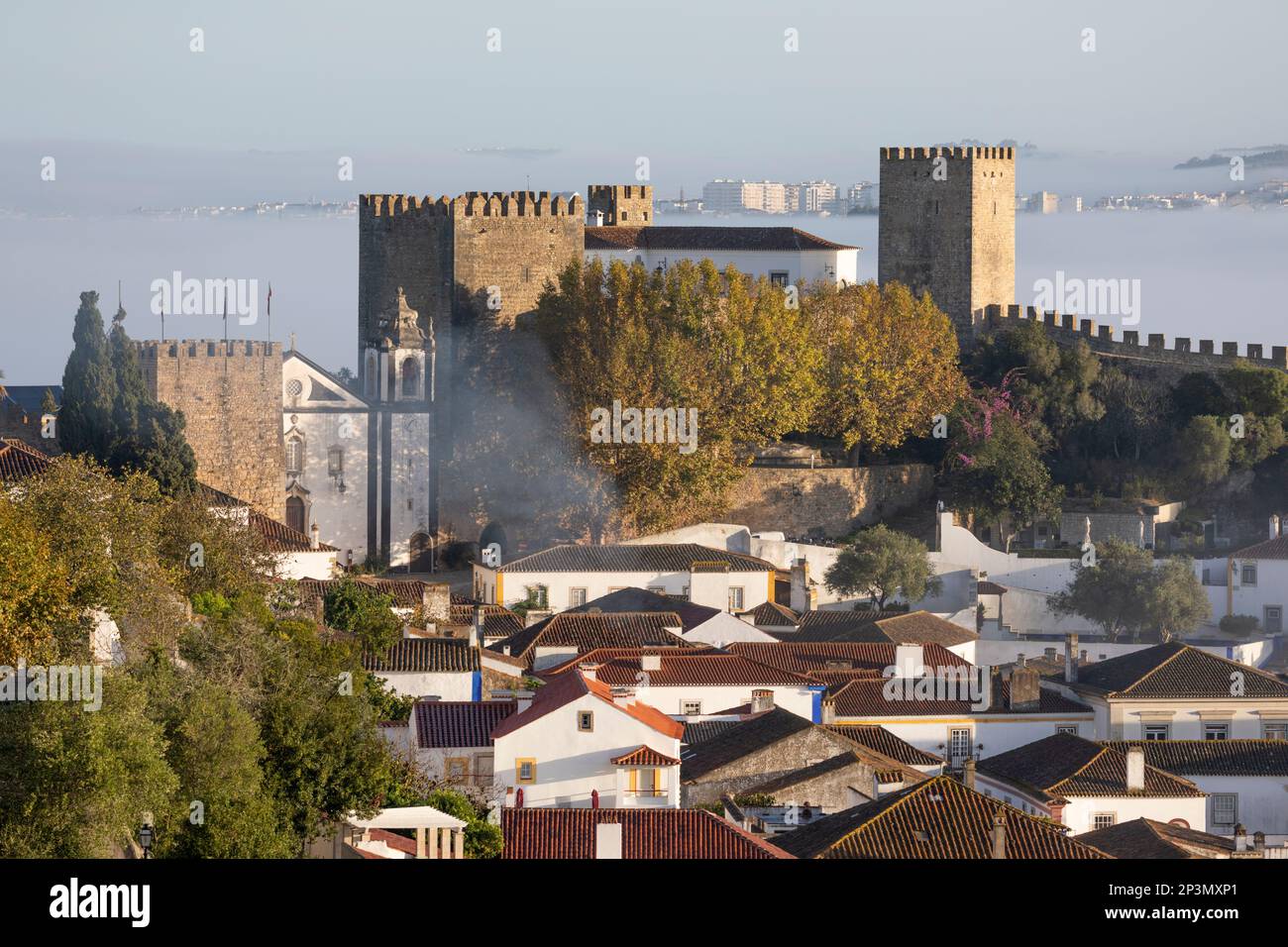 Vista sobre el casco antiguo y las murallas con el castillo de Óbidos en la niebla de la mañana, Óbidos, Región Central, Portugal, Europa Foto de stock