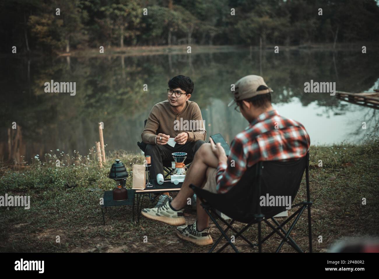 joven dos-hombre disfrutando de goteo de café en el día de camping Foto de stock