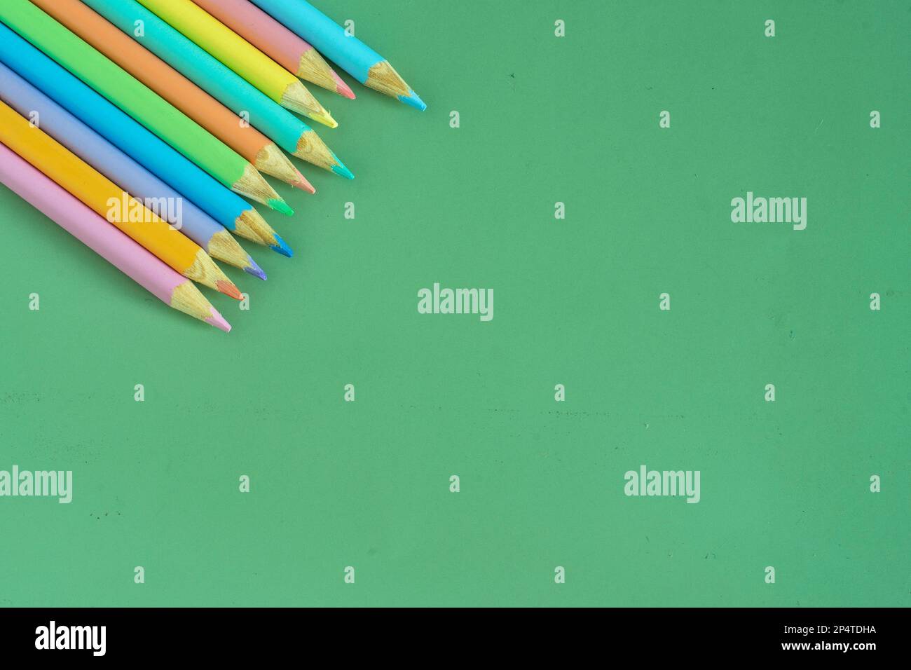 Lápices de colores pastel, vista superior sobre fondo verde, concepto de  ilustración, fondo y educación y vuelta a la escuela Fotografía de stock -  Alamy