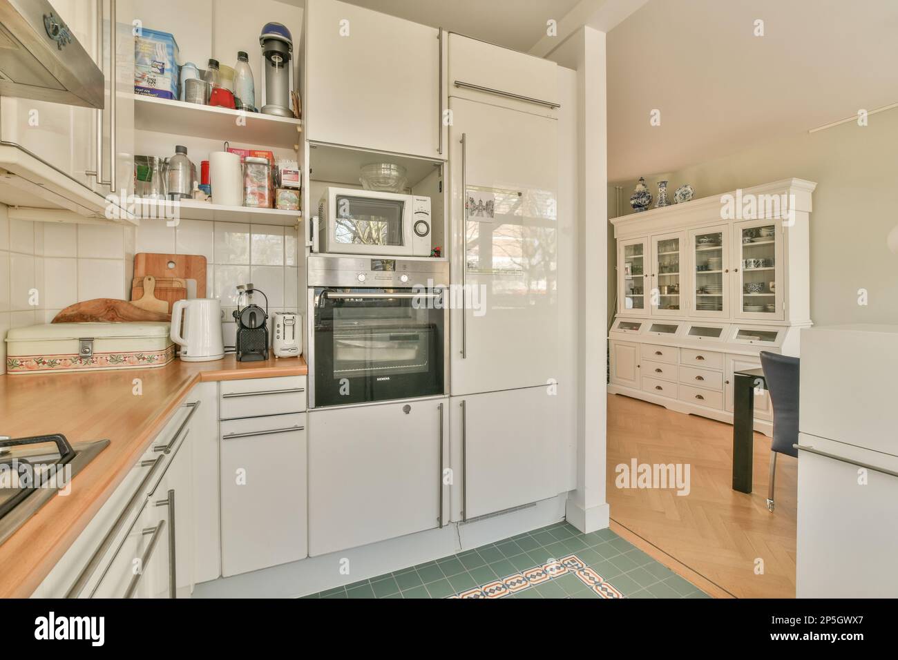 una cocina con armarios blancos y encimeras de madera en el piso frente al  horno, microondas y lavavajillas Fotografía de stock - Alamy