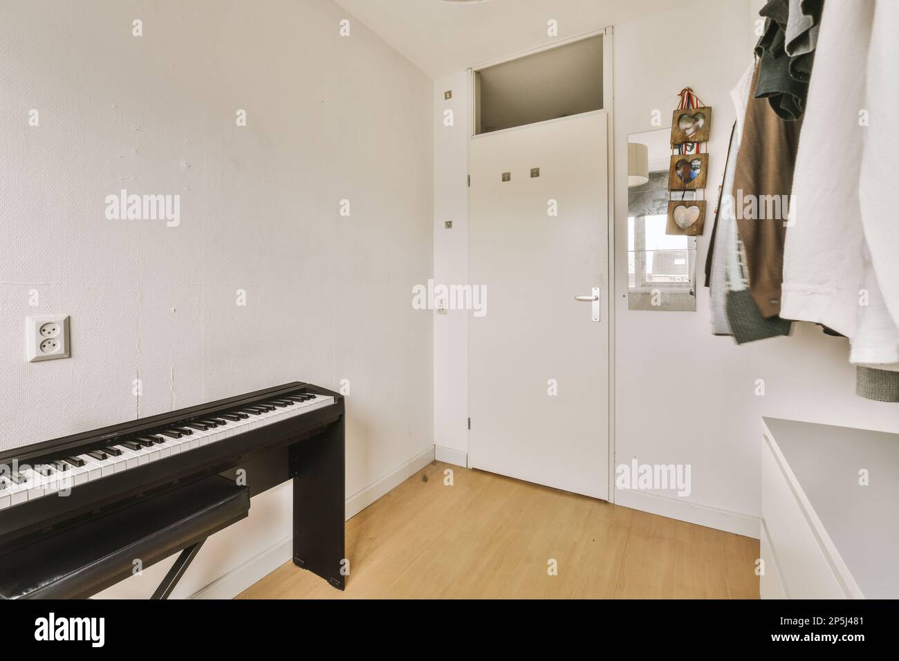 una habitación vacía con un piano y ropa colgada en la pared frente a la  puerta a la izquierda Fotografía de stock - Alamy