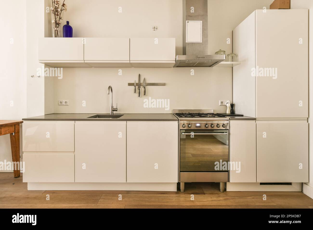 una cocina con armarios blancos y electrodomésticos en la pared por encima  del fregadero es un horno, lavavajillas y estufa Fotografía de stock - Alamy