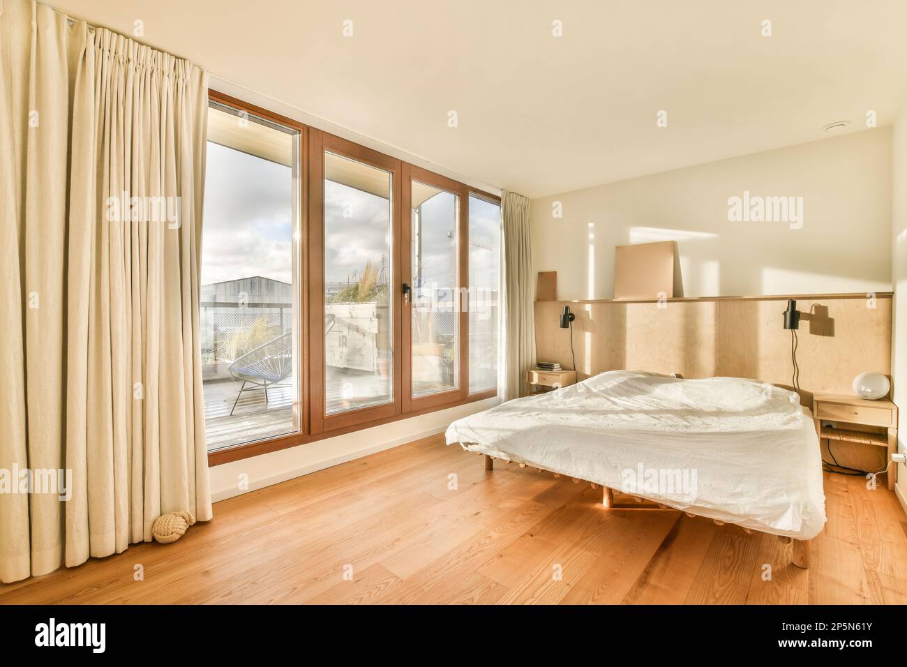 un dormitorio con pisos de madera y puerta corredera de vidrio que se abre  al balcón a una zona de patio exterior Fotografía de stock - Alamy