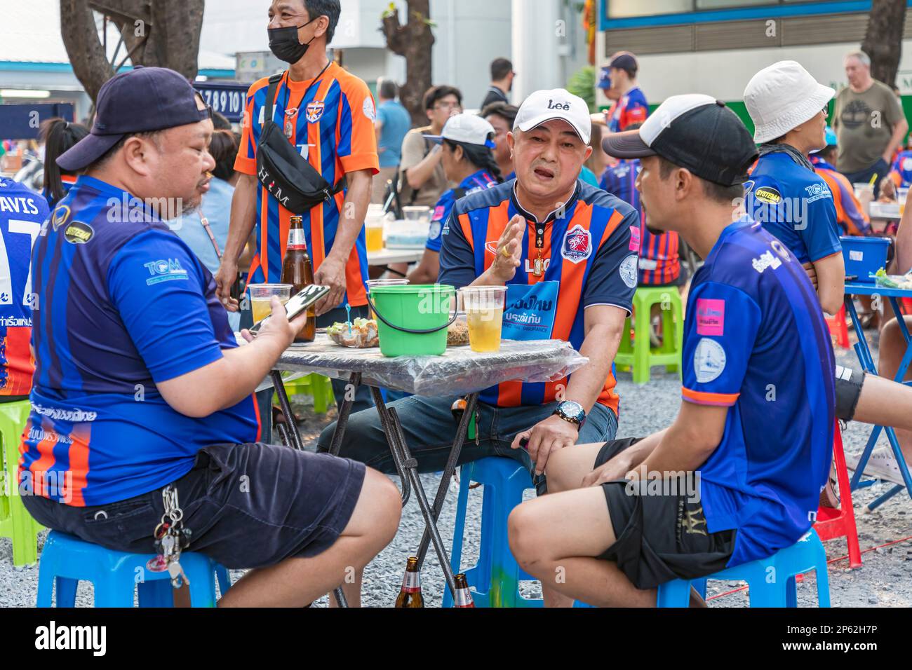 Aficionados al fútbol tailandés comiendo y bebiendo antes del partido en casa, Klong Toei, Bangkok, Tailandia Foto de stock