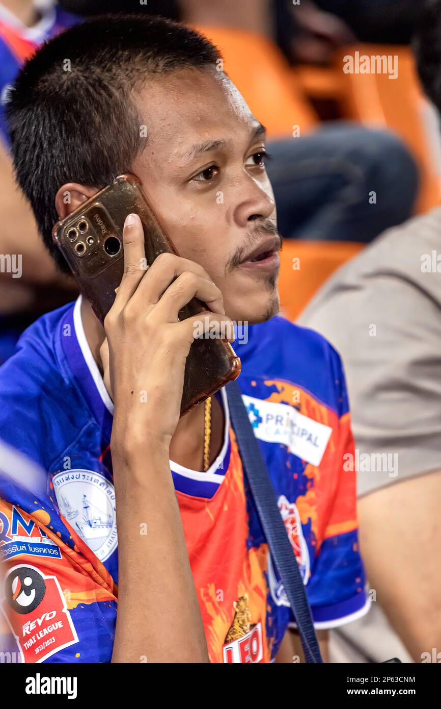 Seguidor del fútbol tailandés en el teléfono móvil durante el partido, estadio PAT, Bangkok Foto de stock