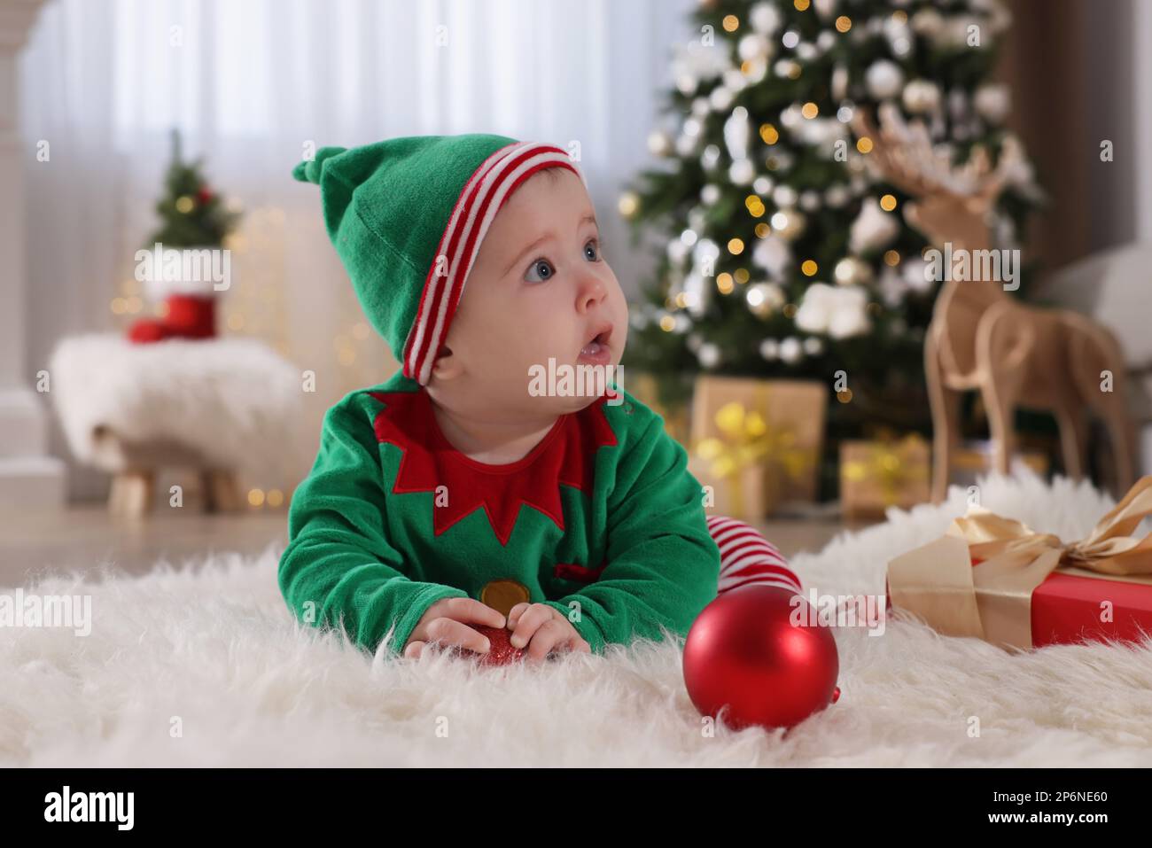 Bebé vistiendo lindo disfraz de elfo en el piso en la habitación decorada  para Navidad Fotografía de stock - Alamy