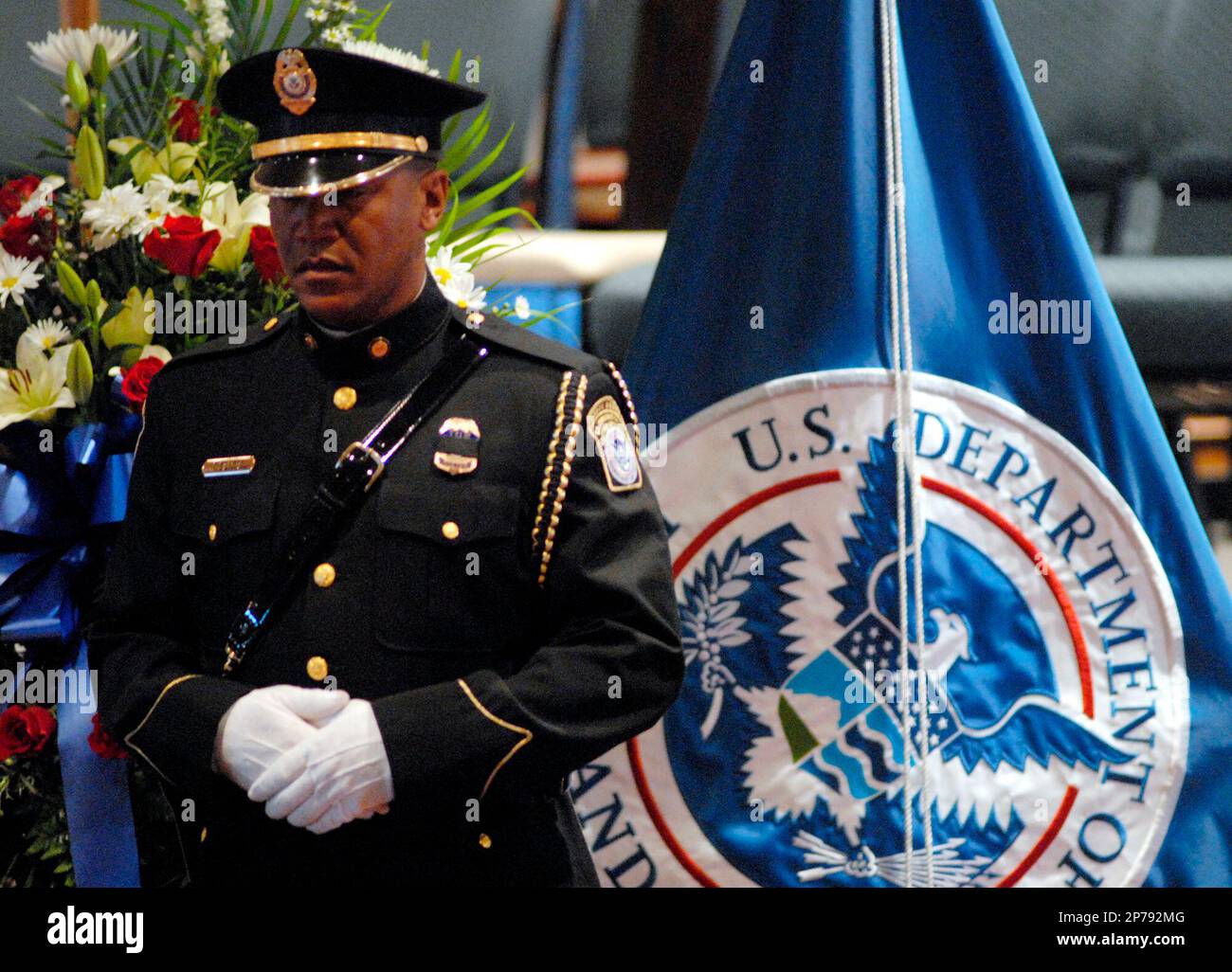 An honor guardsman stands next to a U.S. Department of Homeland Security flag and the casket of