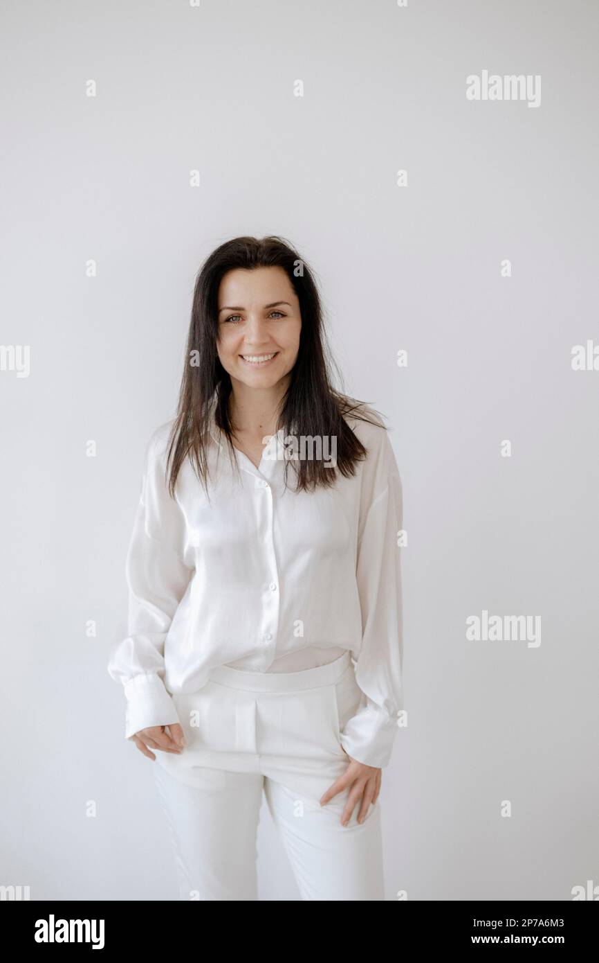 Mujer de pelo oscuro 35+, en camisa blanca y pantalón blanco Fotografía de  stock - Alamy