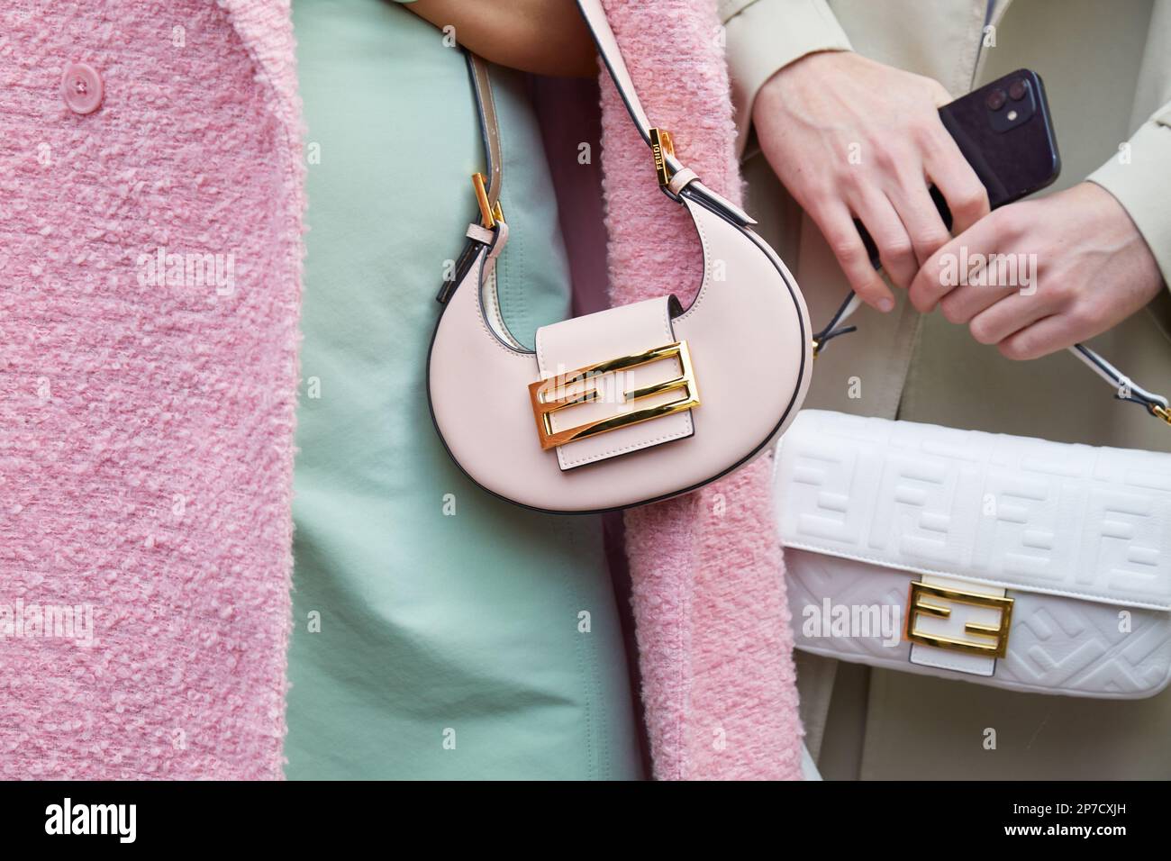 MILÁN, ITALIA - 22 DE FEBRERO de 2023: Mujer con bolso de piel Fendi rosa pálido y hombre con bolso blanco con estampado de logotipo antes del desfile de Fendi, Milan Fas Foto de stock