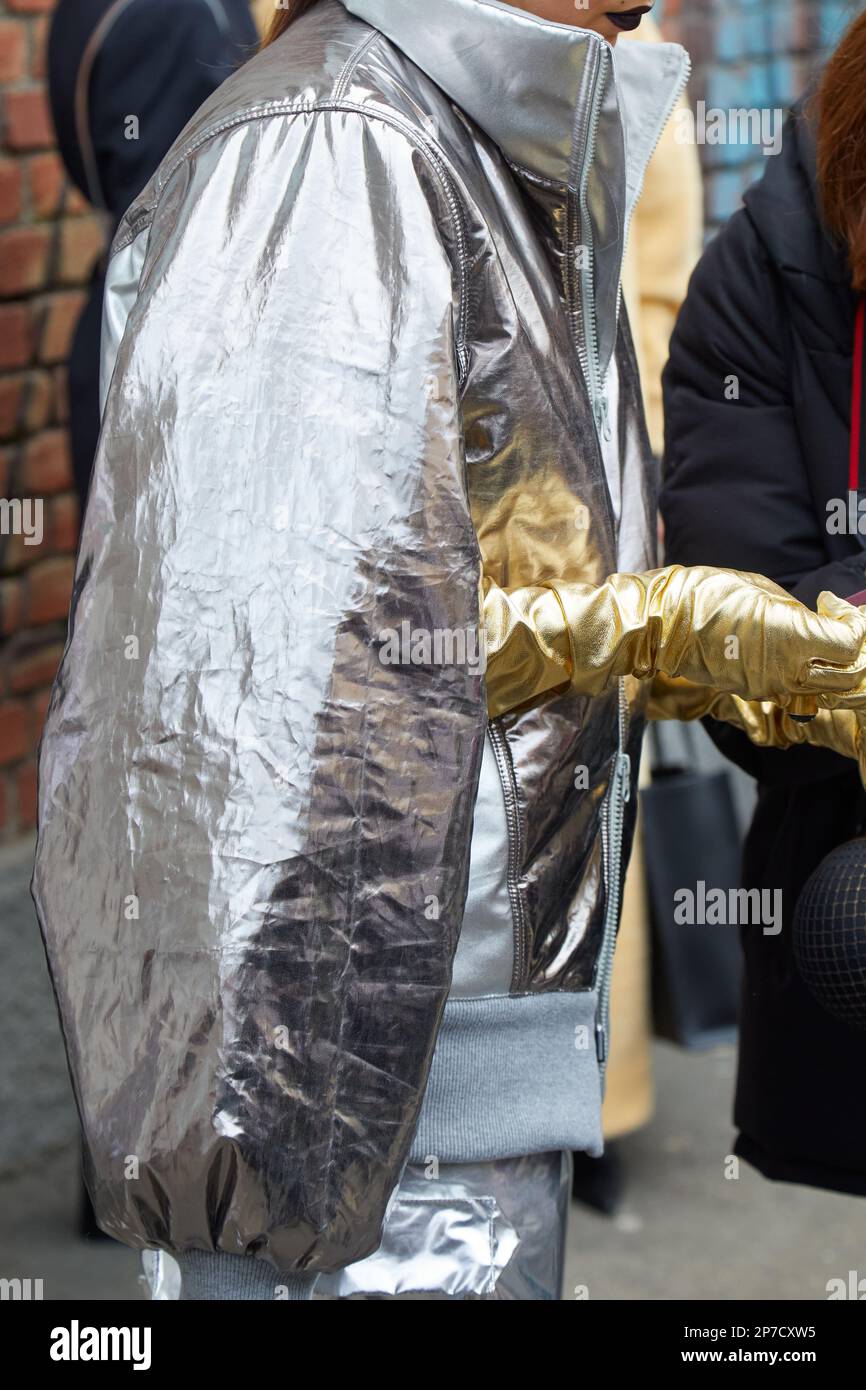 MILÁN, ITALIA - 22 DE FEBRERO de 2023: Mujer con chaqueta plateada y guantes dorados antes del desfile de Fendi, estilo callejero de la Semana de la Moda de Milán Foto de stock